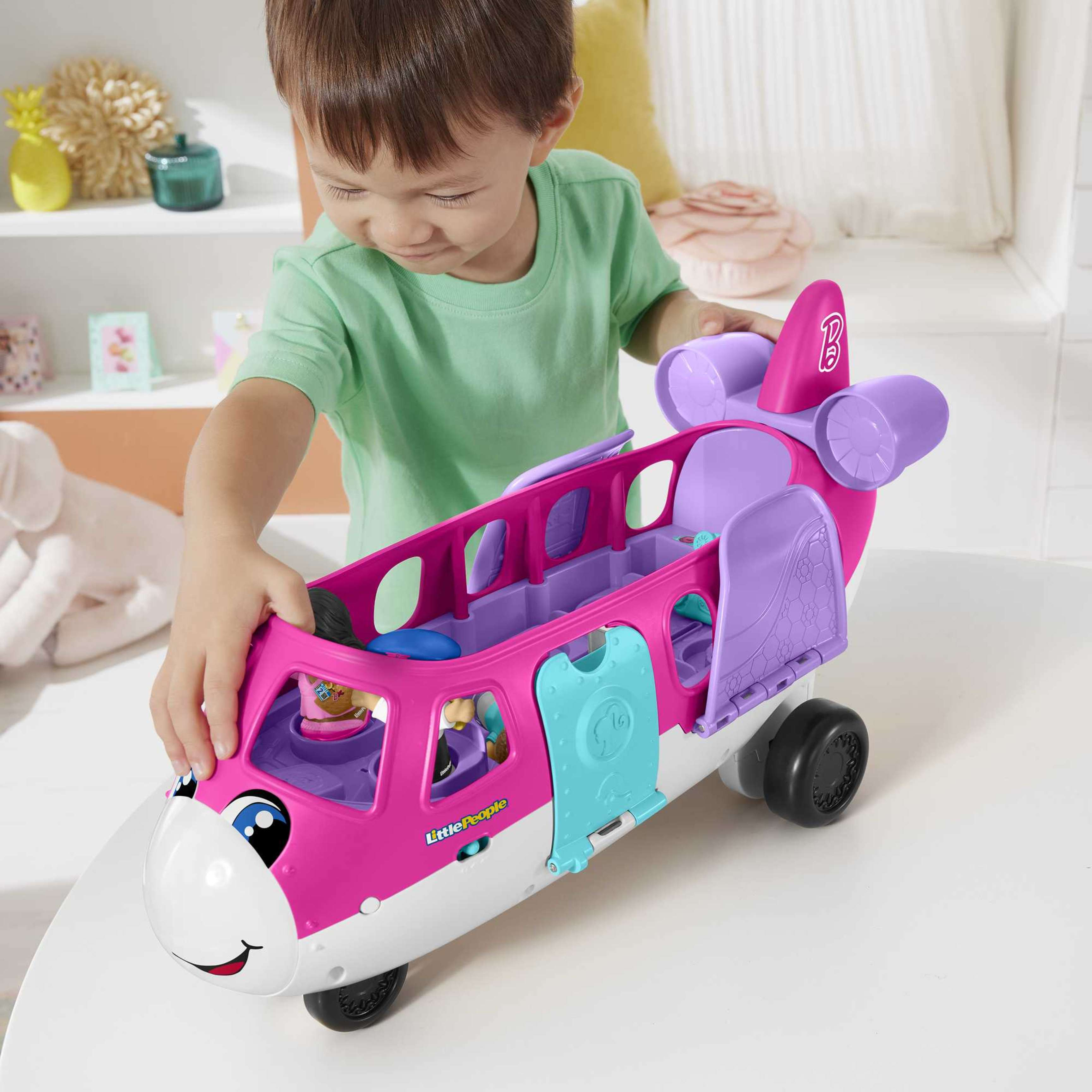 Dziecko bawiące się różową zabawką samolotem, z ludźmi w środku.