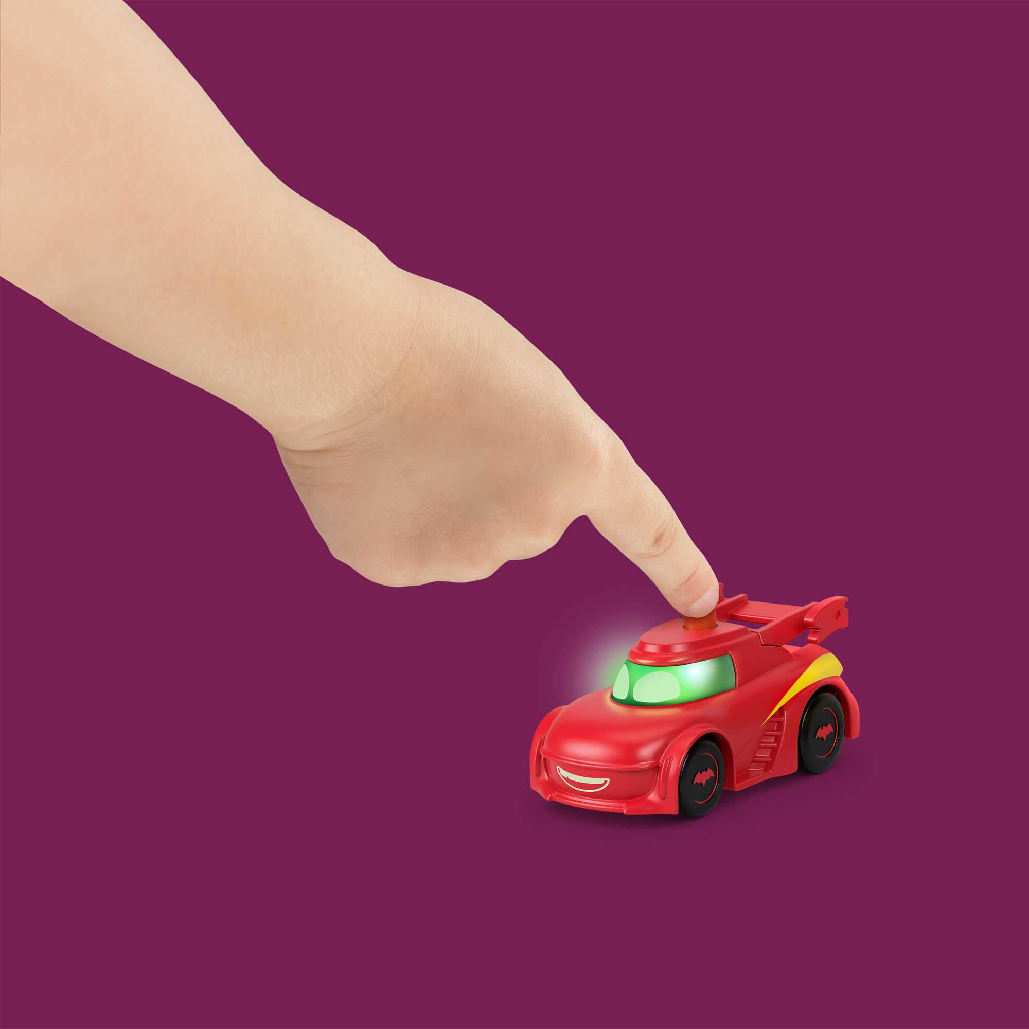 Ręka wskazująca na czerwony samochodzik z zielonymi światłami na fioletowym tle.