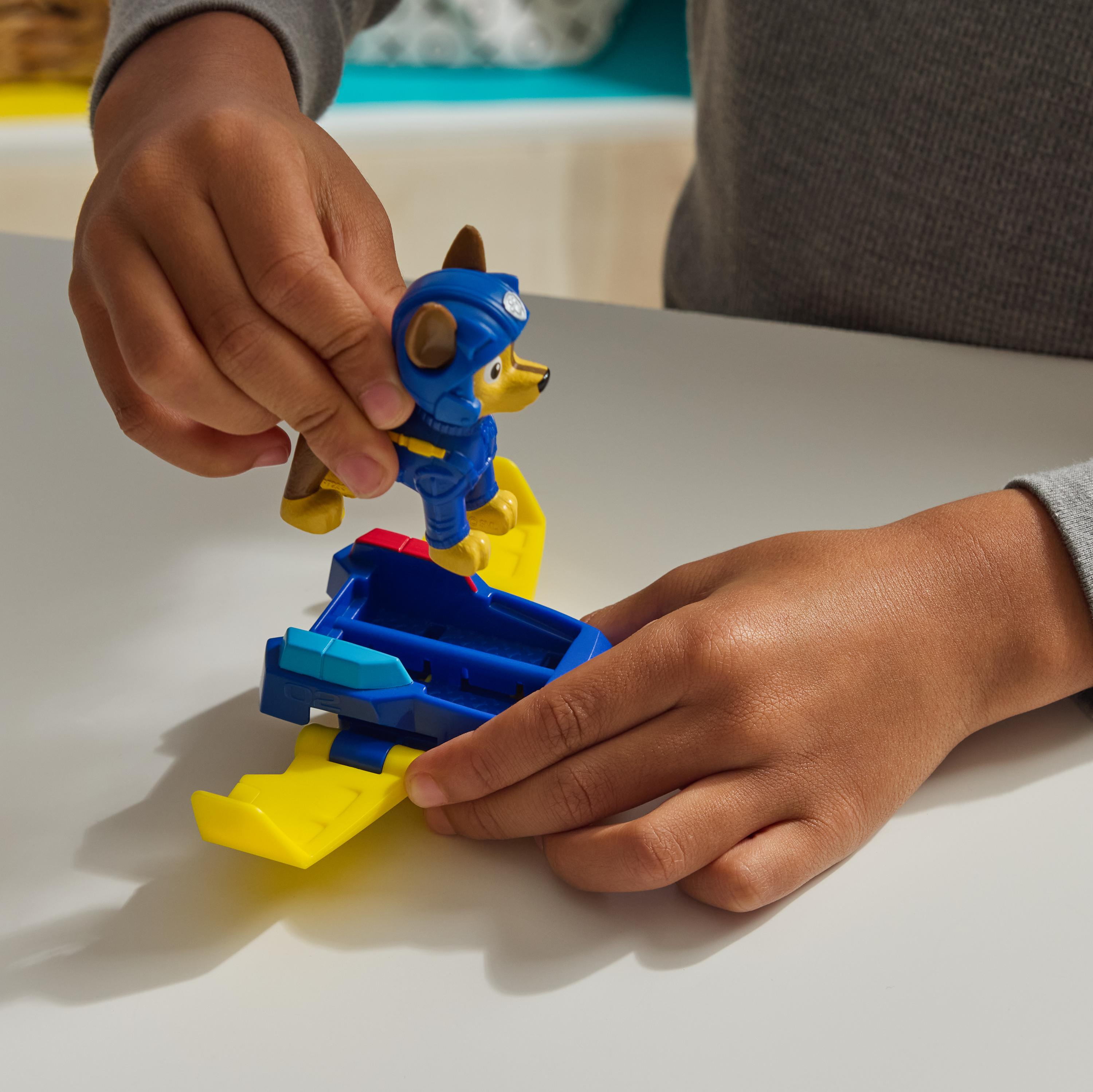 Kinderhände spielen mit einem Paw Patrol Spielzeugflugzeug und einer Hundefigur.