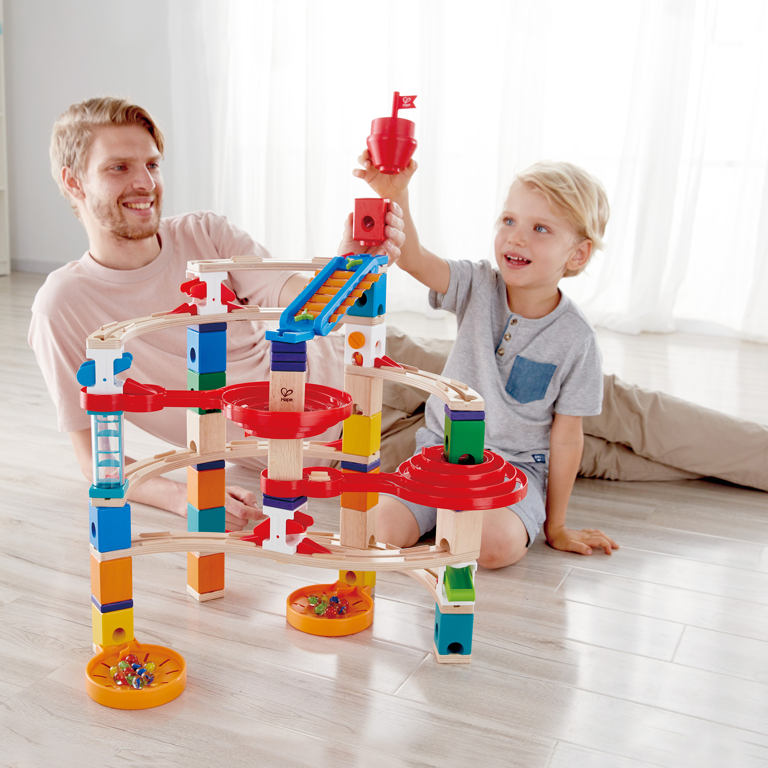 Ojciec i syn bawią się zabawką toru kulkowego, uśmiechając się.