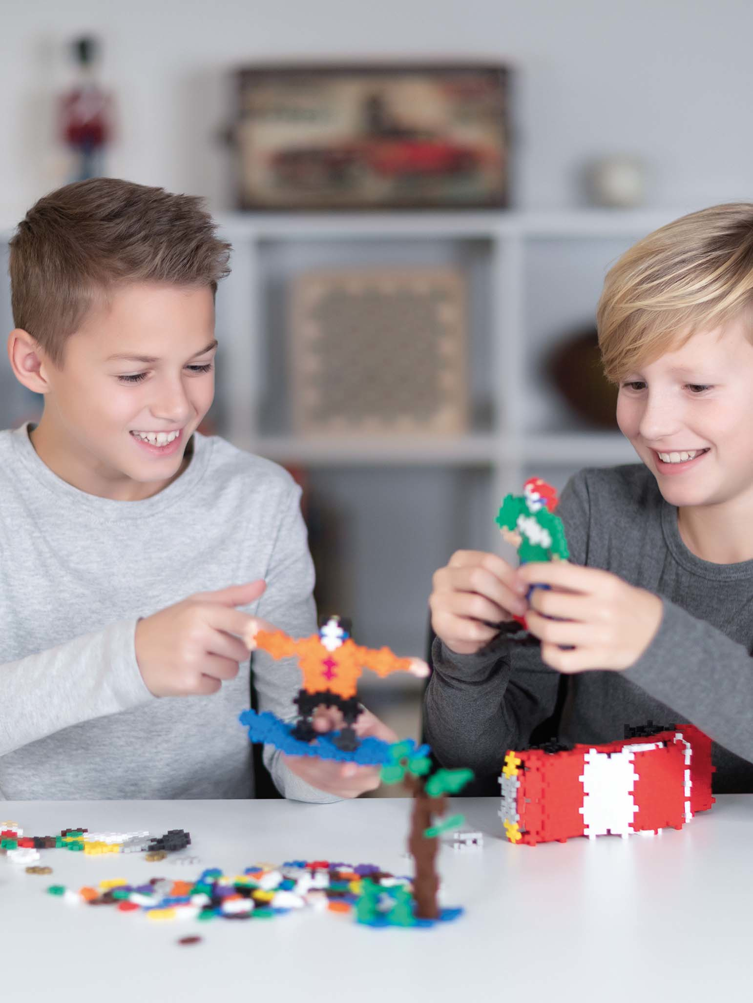 Zwei Jungen spielen mit bunten Bausteinen. Einer hält einen Skater, der andere eine Figur.