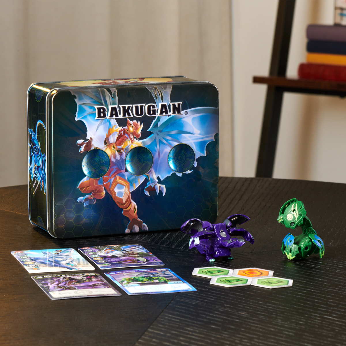 Bakugan-Spielbox mit Karten und Spielfiguren auf einem dunklen Tisch. Die Box hat ein Drachenbild.