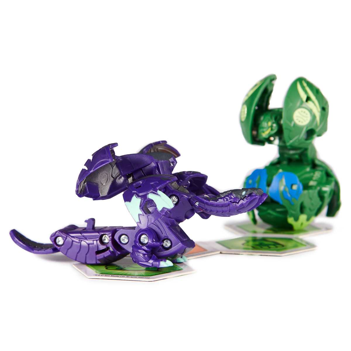Zwei Bakugan-Figuren auf zwei Karten. Die Figuren sind lila und grün.