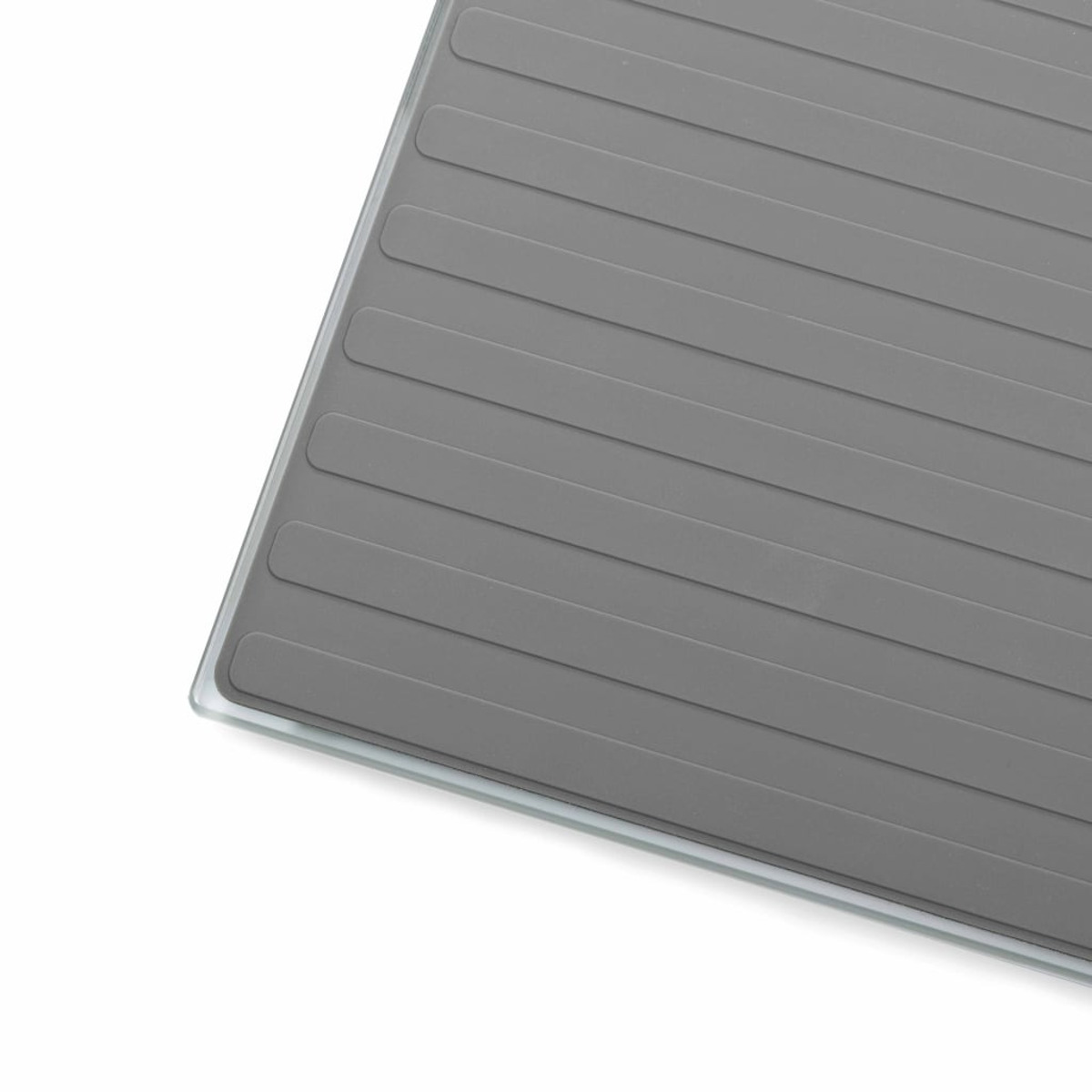 Gros plan sur une surface grise, striée, probablement une plateforme de balance. Fond blanc.