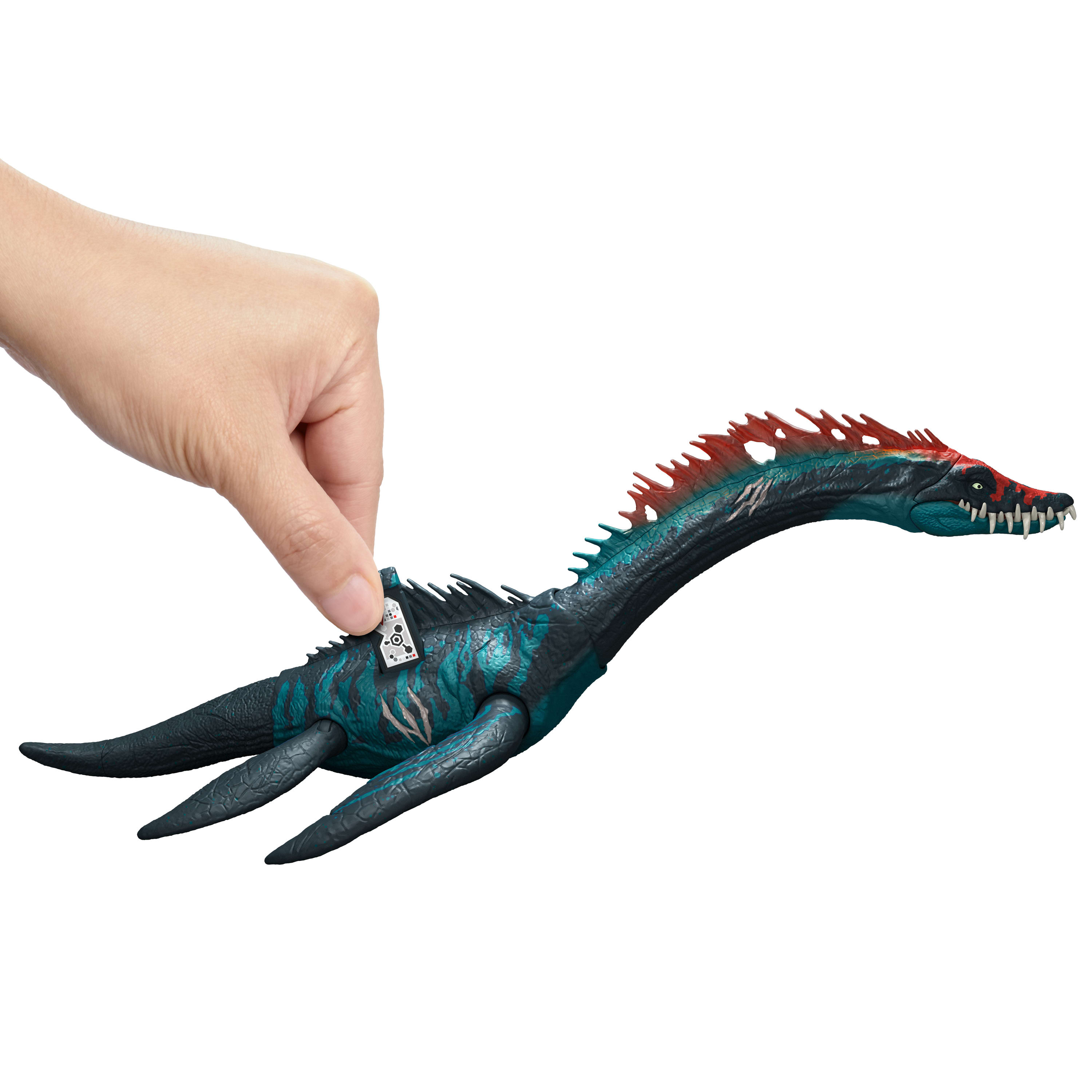 Una mano sostiene un juguete de dinosaurio azul y turquesa. El juguete está en primer plano sobre fondo blanco.