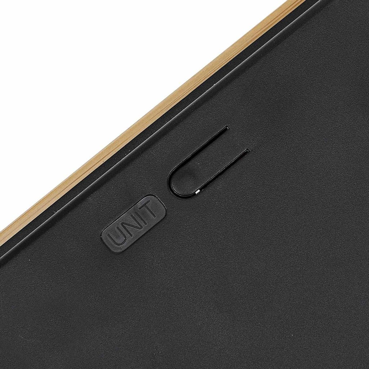 Zbliżenie czarnej podstawy wagi ze spinaczem i napisem 'UNIT'.