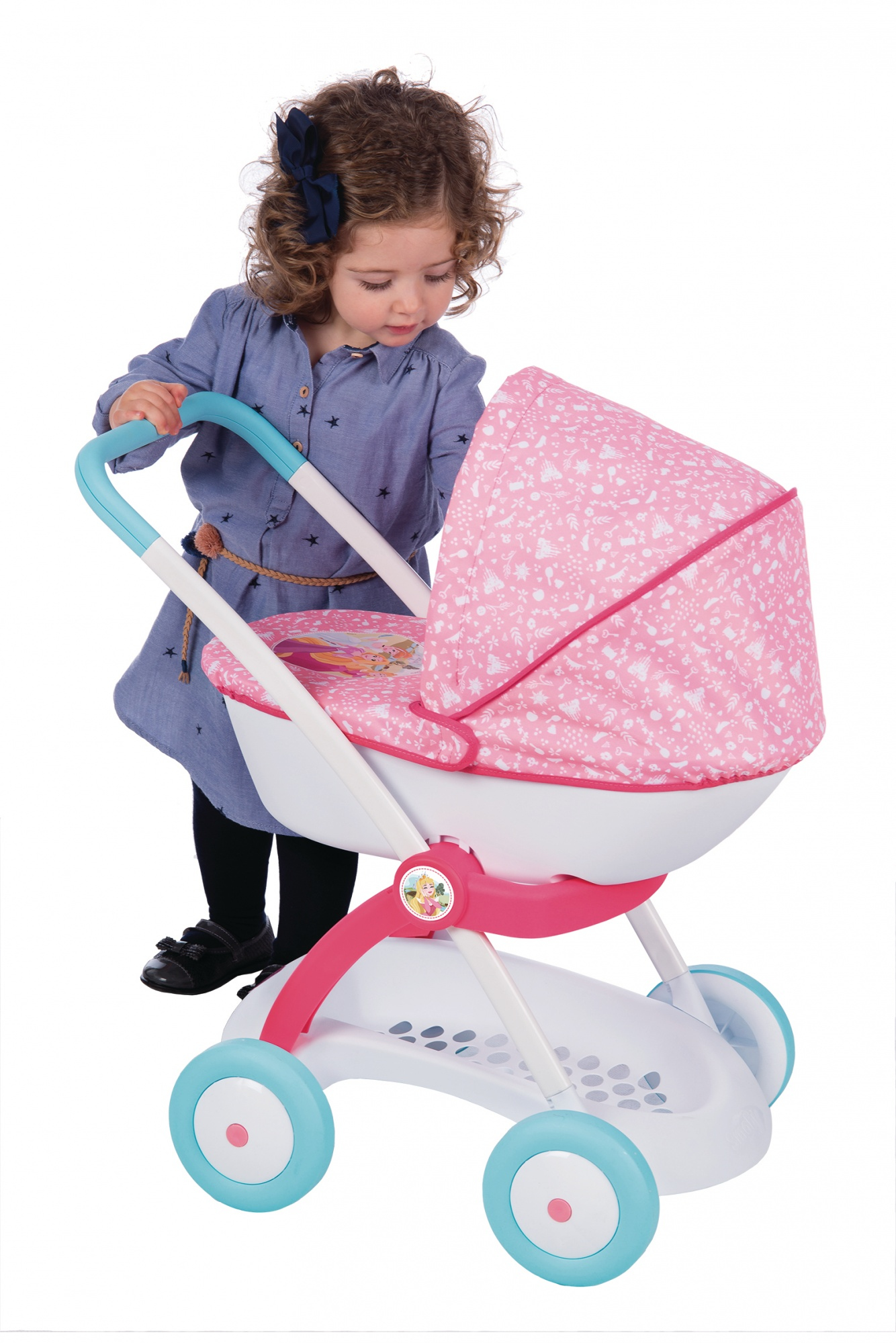 Mała dziewczynka pchająca różowy wózek dla lalek.