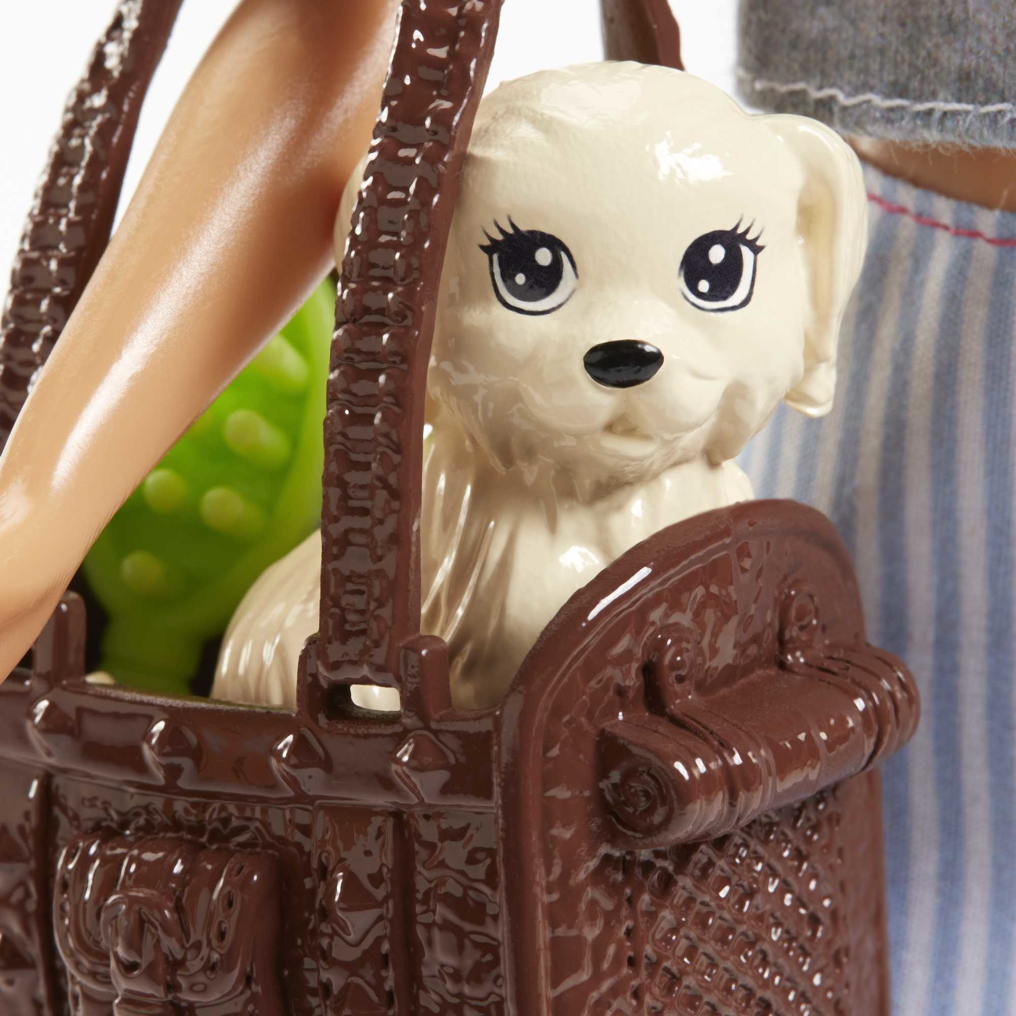 Eine Barbie-Puppe mit einem Welpen in einem braunen Korb. Der Hund ist weiß mit schwarzen Augen.
