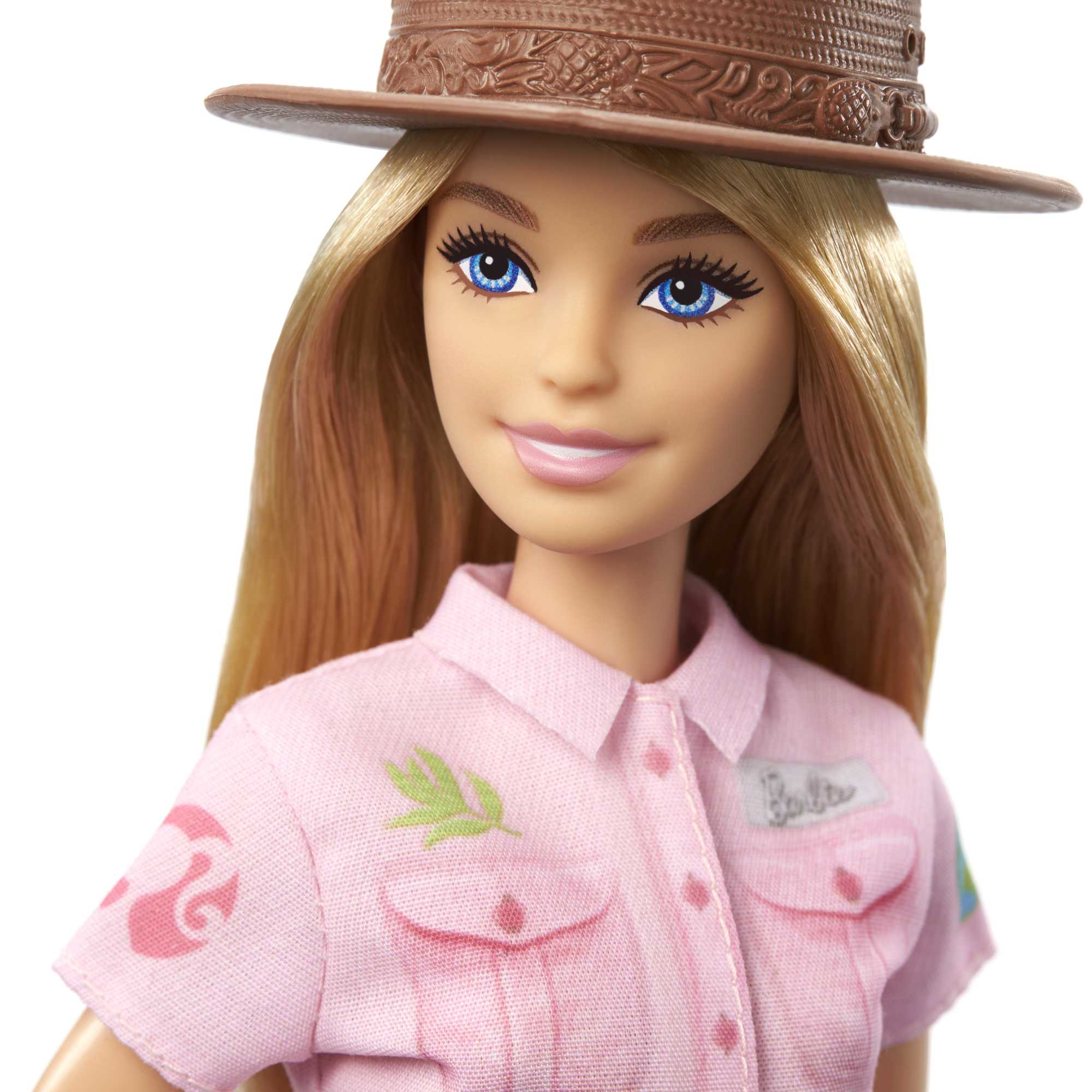 Nahaufnahme des Gesichts einer Barbie-Puppe mit blonden Haaren, blauen Augen und einem braunen Hut. Sie trägt ein rosa Hemd.