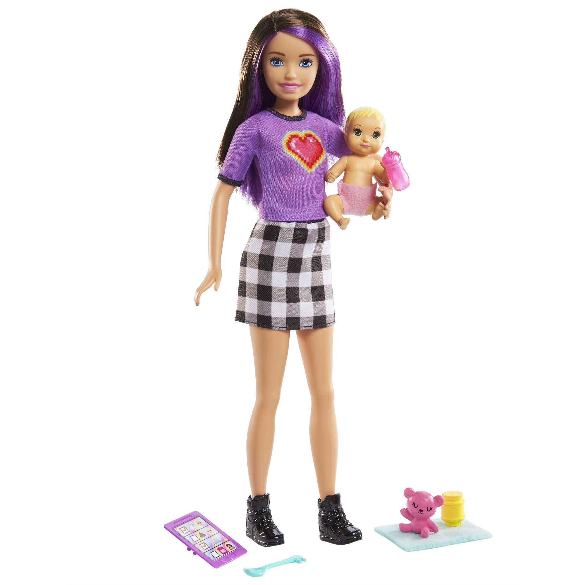 Una bambola Barbie che tiene un bambolotto con accessori su una superficie bianca, con sfondo rosa.