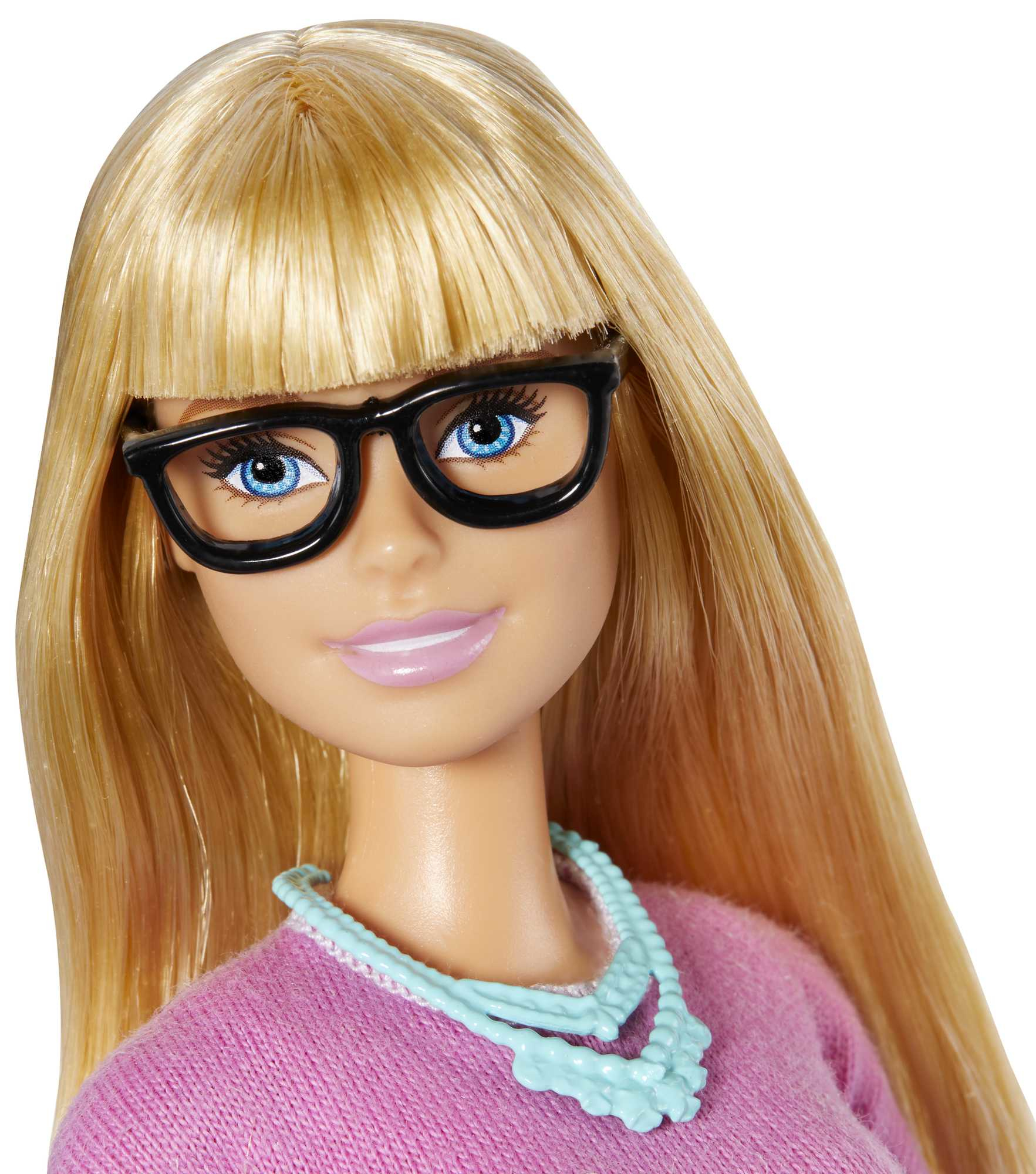 Zbliżenie twarzy lalki Barbie w okularach, z blond włosami i naszyjnikiem. Ma na sobie różową koszulę.