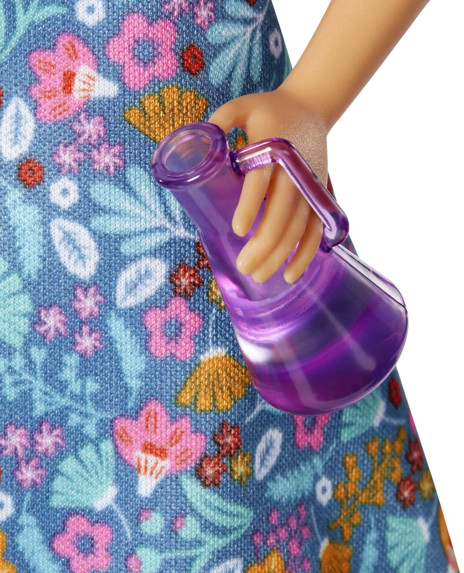 Zbliżenie lalki Barbie trzymającej fioletowy, przezroczysty zlew, ubranej w kwiecistą sukienkę.