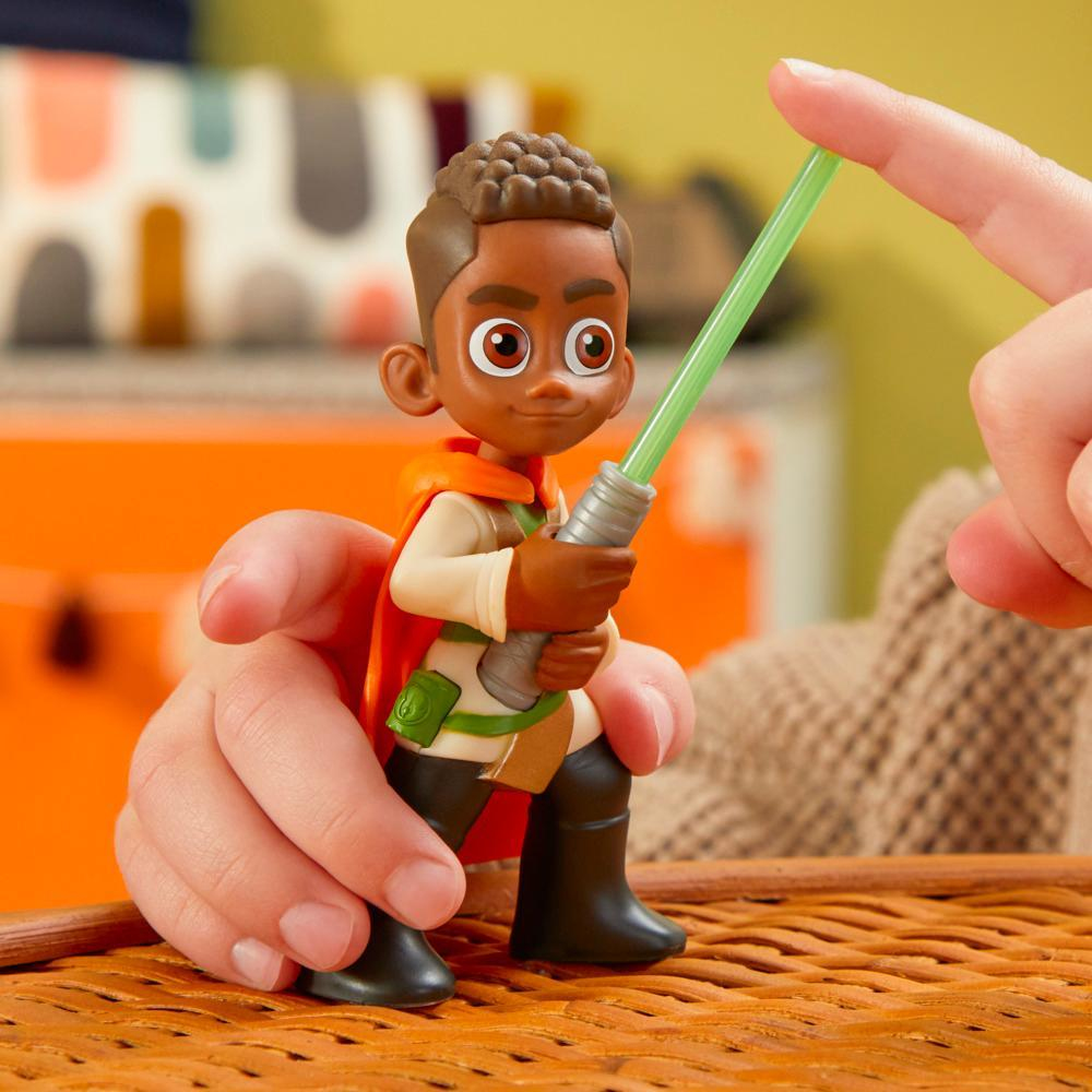 La mano di un bambino che tiene una figura Jedi di Star Wars con una spada laser verde.