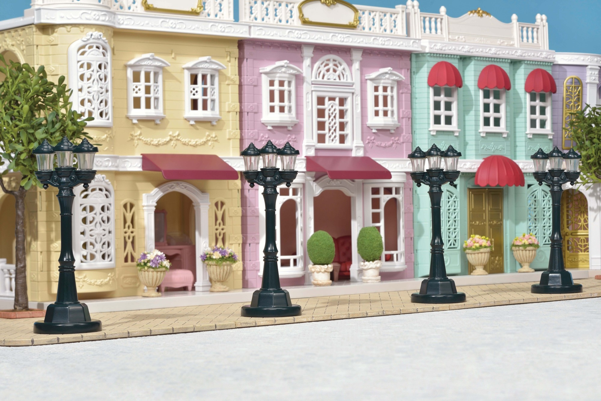 Model ulicy z kolorowymi budynkami, markizami i latarniami ulicznymi. Niebo w tle.