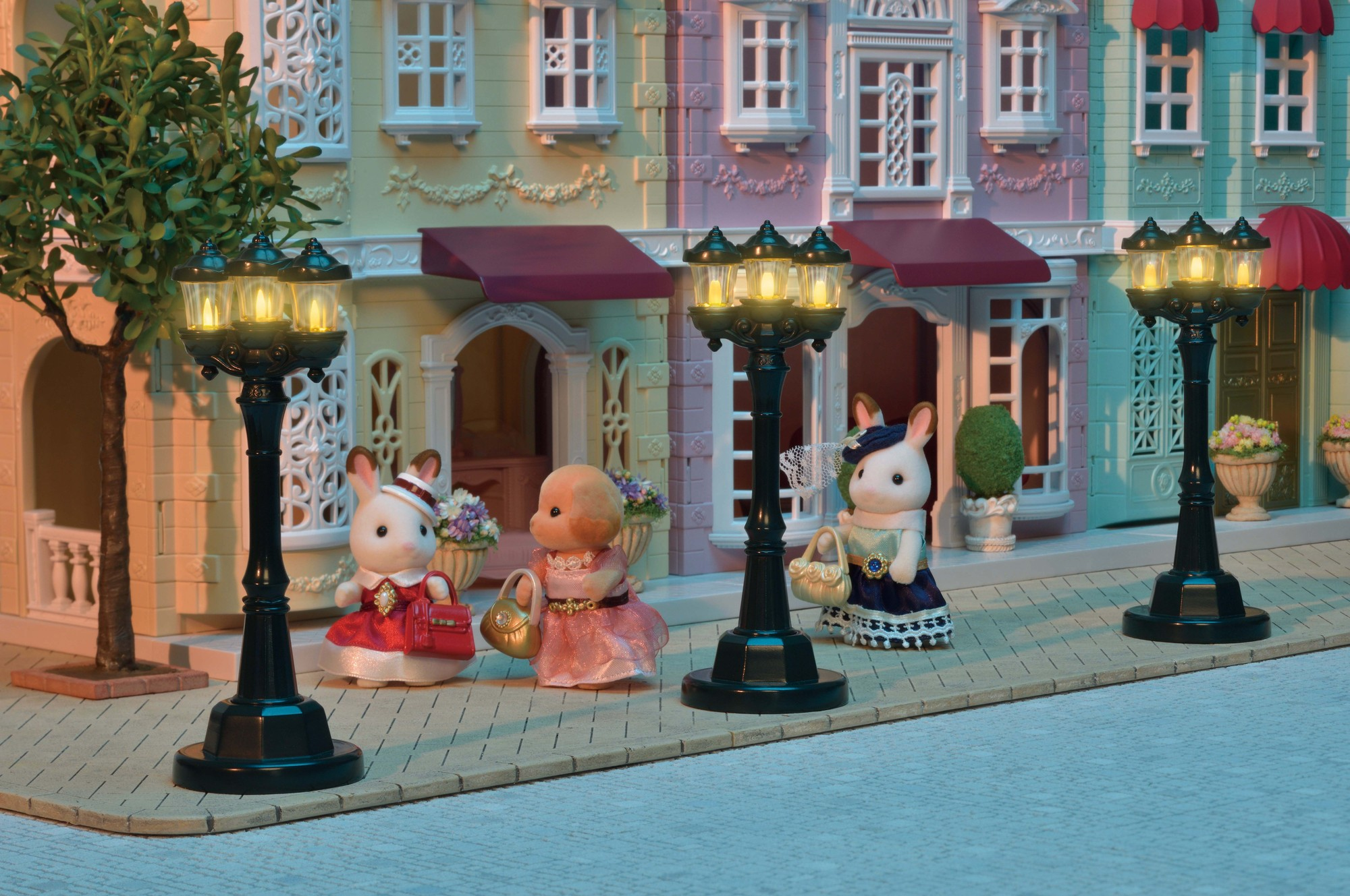 Scena uliczna z figurkami zabawek, w tym królikami, obok oświetlonych latarni ulicznych i budynków.