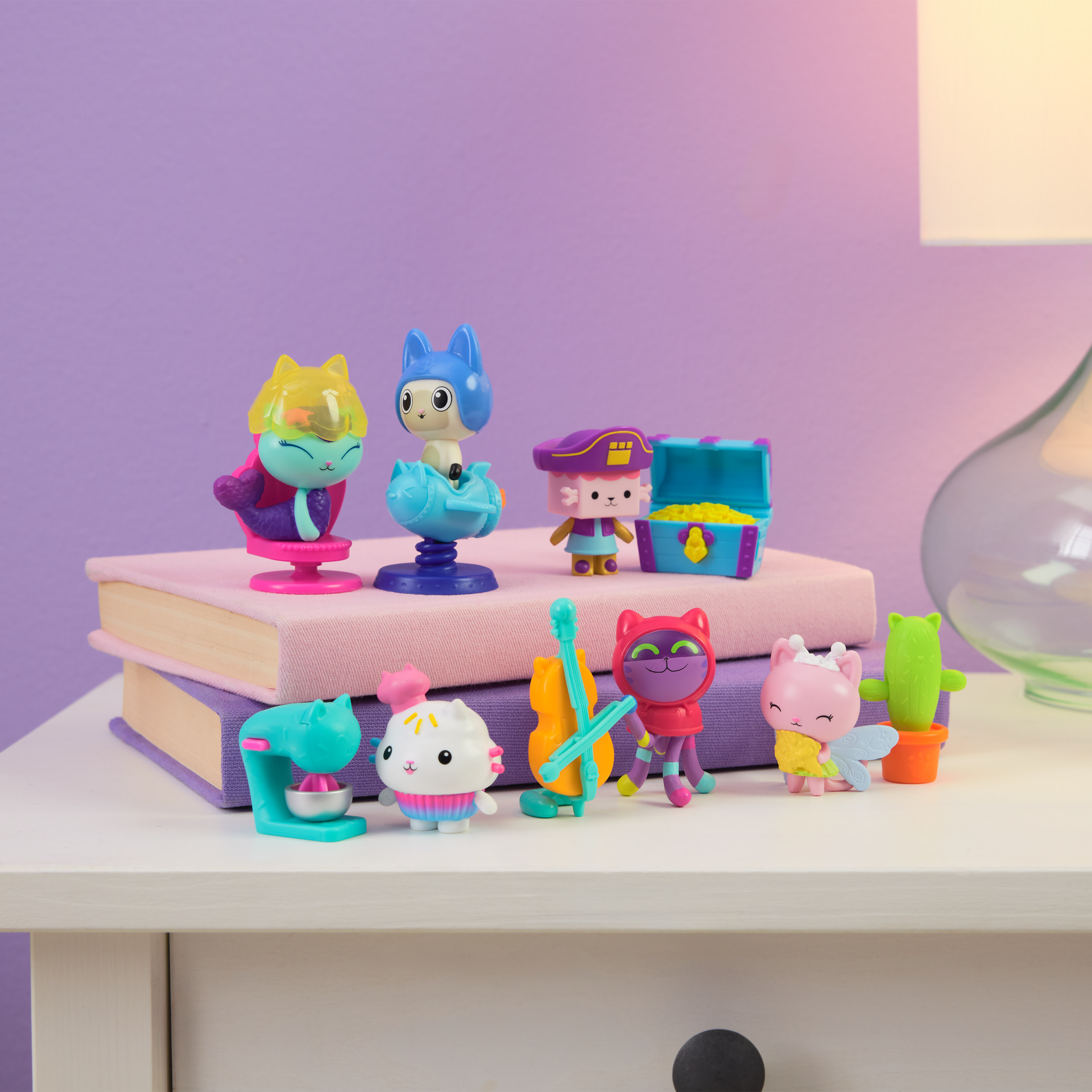 Colección de figuras de Gabby's Dollhouse sobre una mesa. Gatos, accesorios y libros en el fondo.