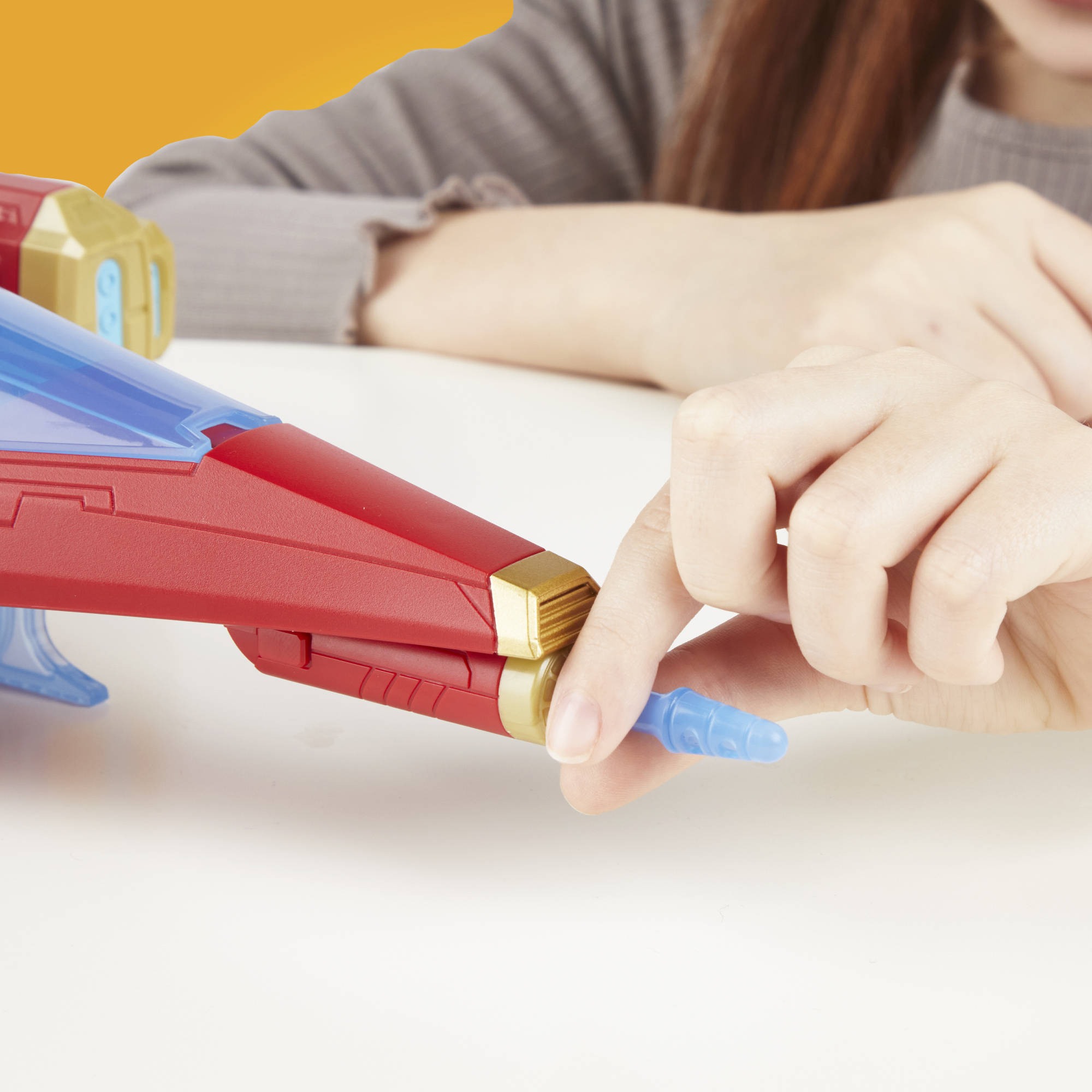 Ręka trzymająca niebieską dyszę na czerwono-złotym zabawnym statku kosmicznym.