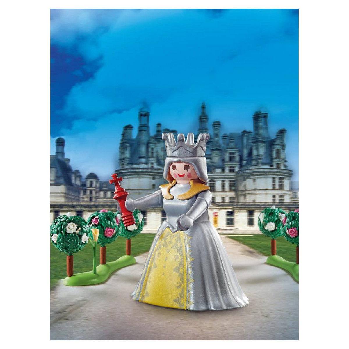 Spielzeug-Königin-Figur mit Krone, rotem Zepter und silbernem Kleid. Hinter einem Schloss mit Bäumen und Pfad.