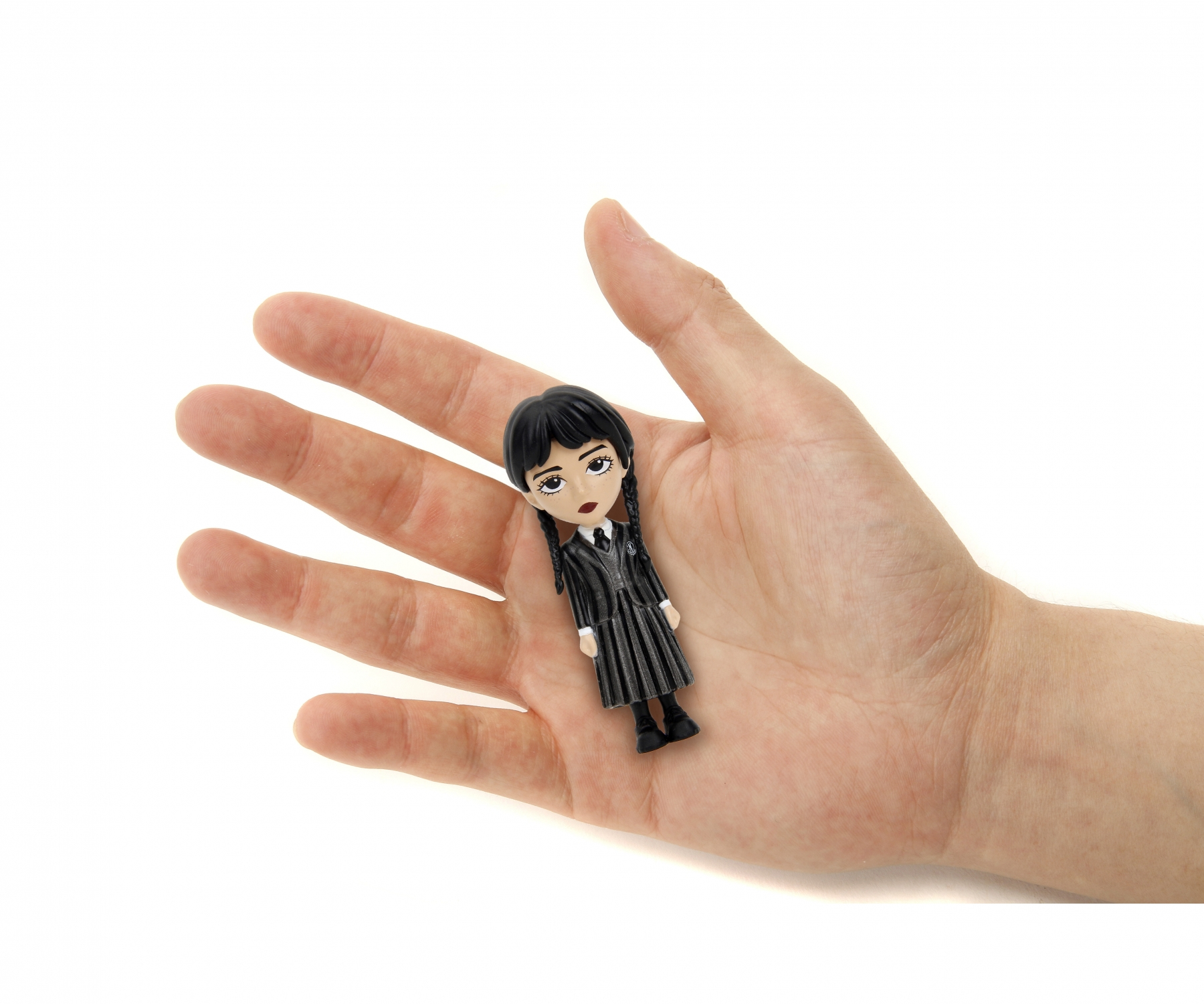 Mała figurka Wednesday Addams w dłoni. Ma na sobie czarną sukienkę i warkocze.