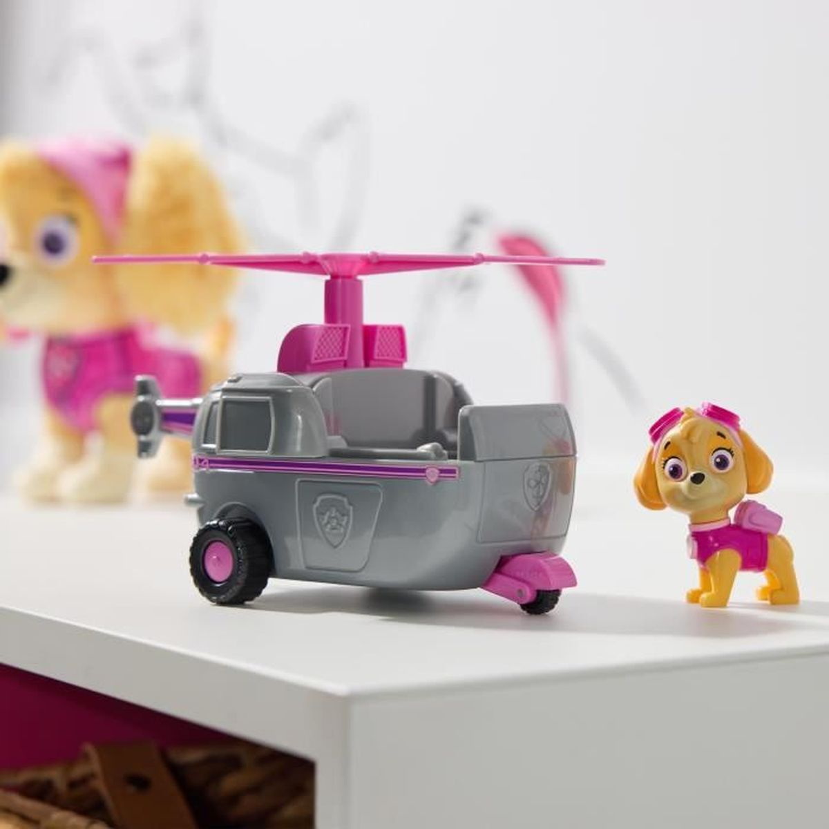 Een speelgoedhelikopter met een gele hondenfiguur erin en een hondenfiguur naast de helikopter.