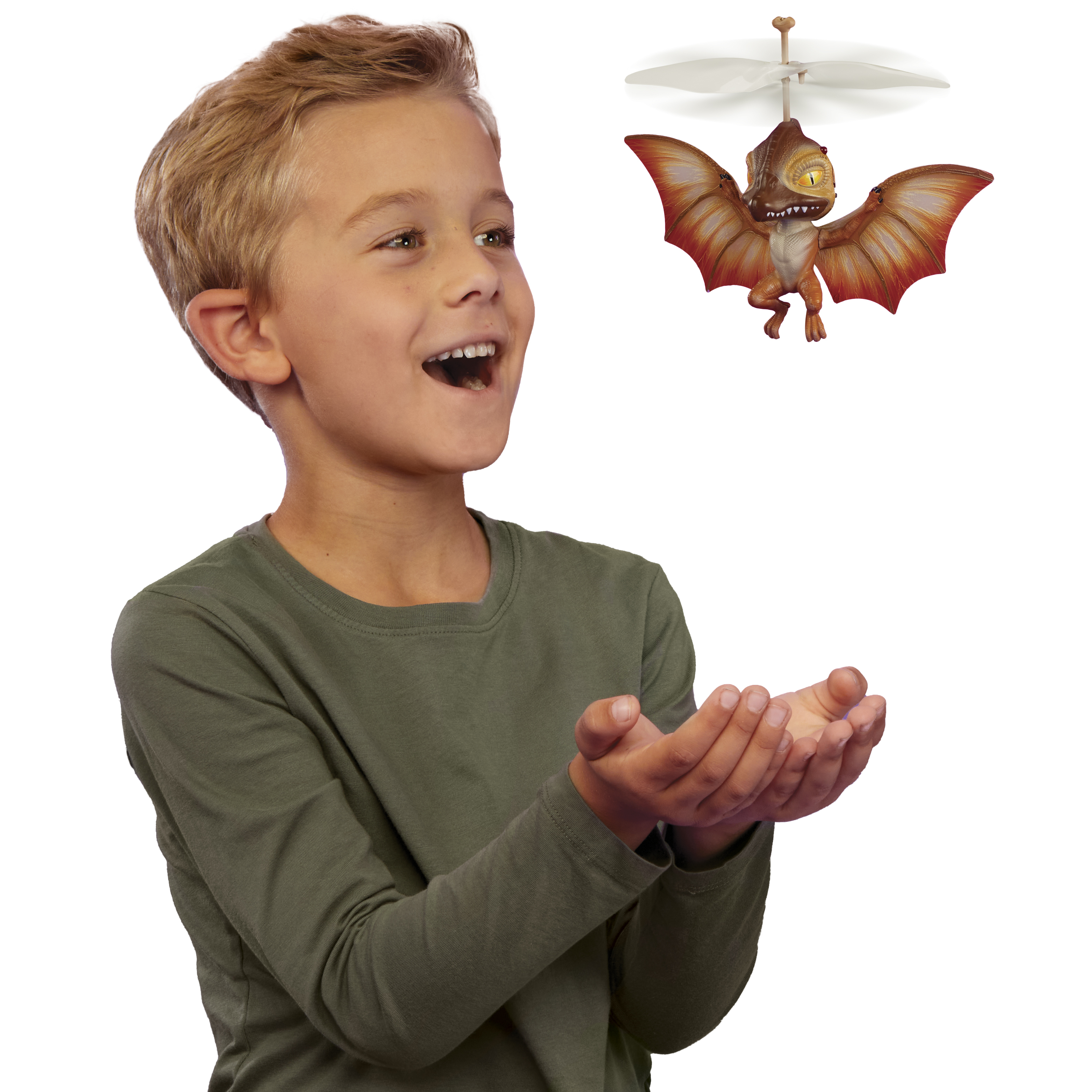 Un niño mira hacia arriba emocionado, con las manos abiertas. Un dragón de juguete con alas rojas vuela.