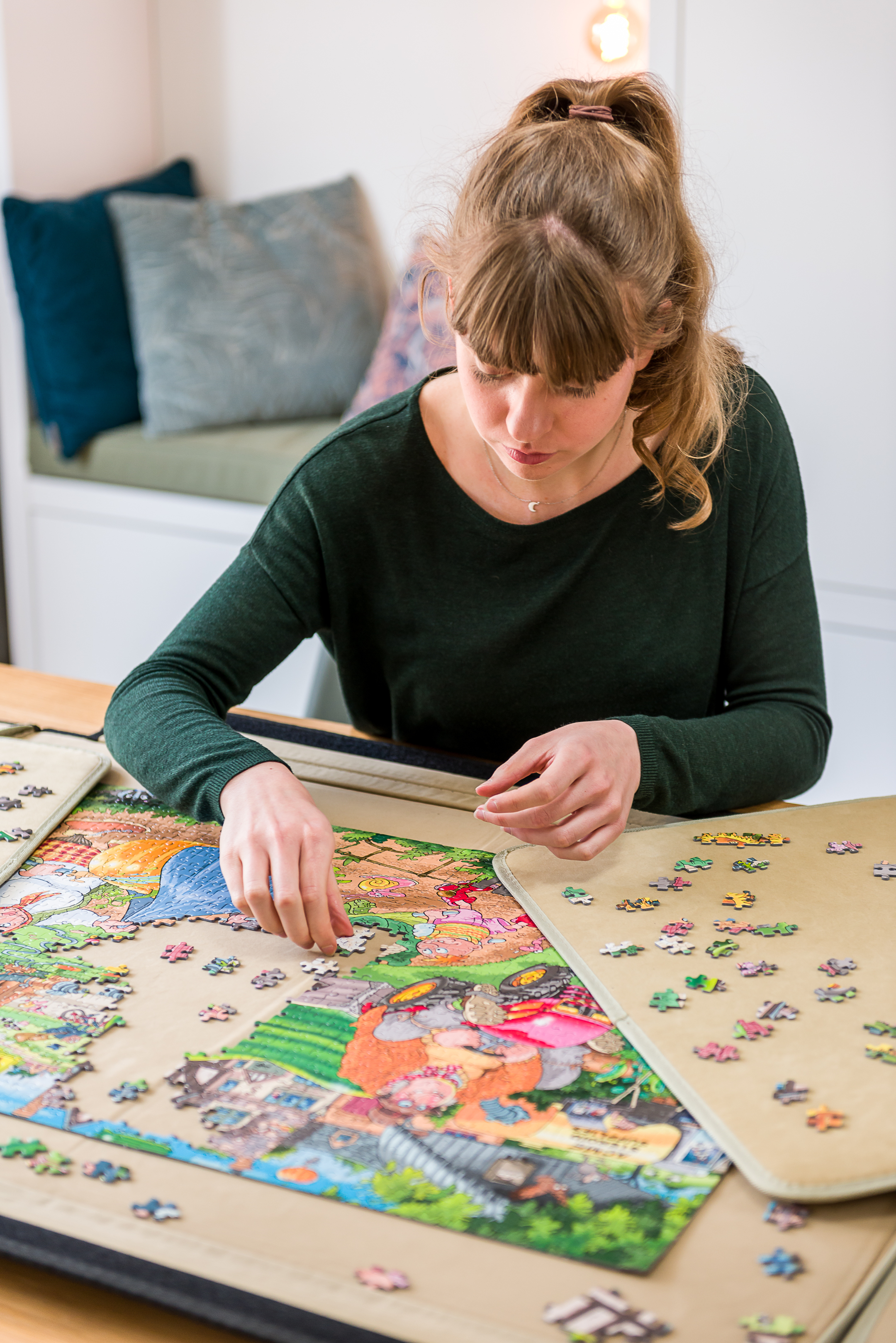 Una persona sta assemblando un puzzle su un tavolo. Diversi pezzi sono sparsi su un tappetino beige.