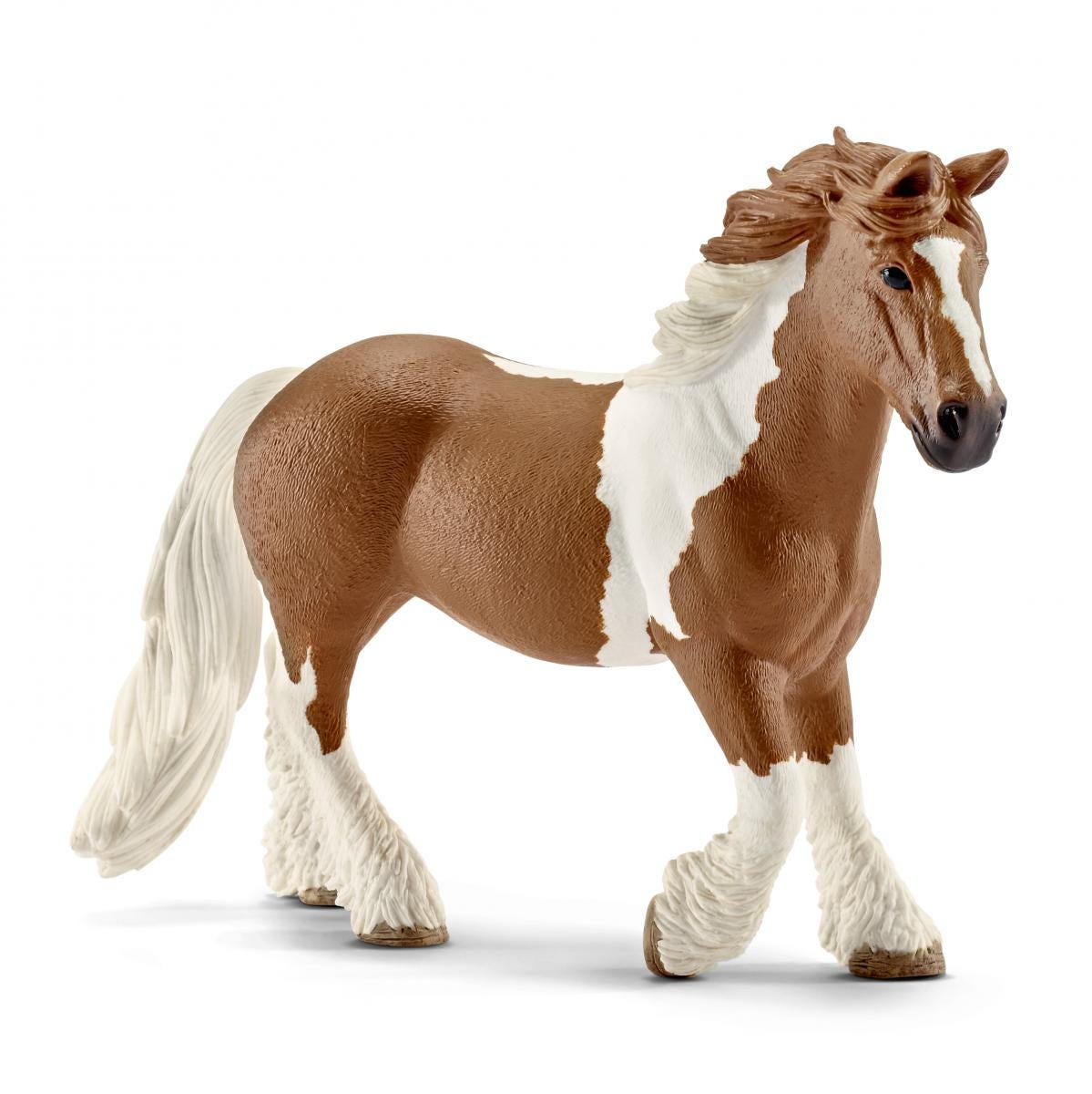 Una statuetta di cavallo marrone e bianco con una criniera fluente, in piedi su una superficie bianca.