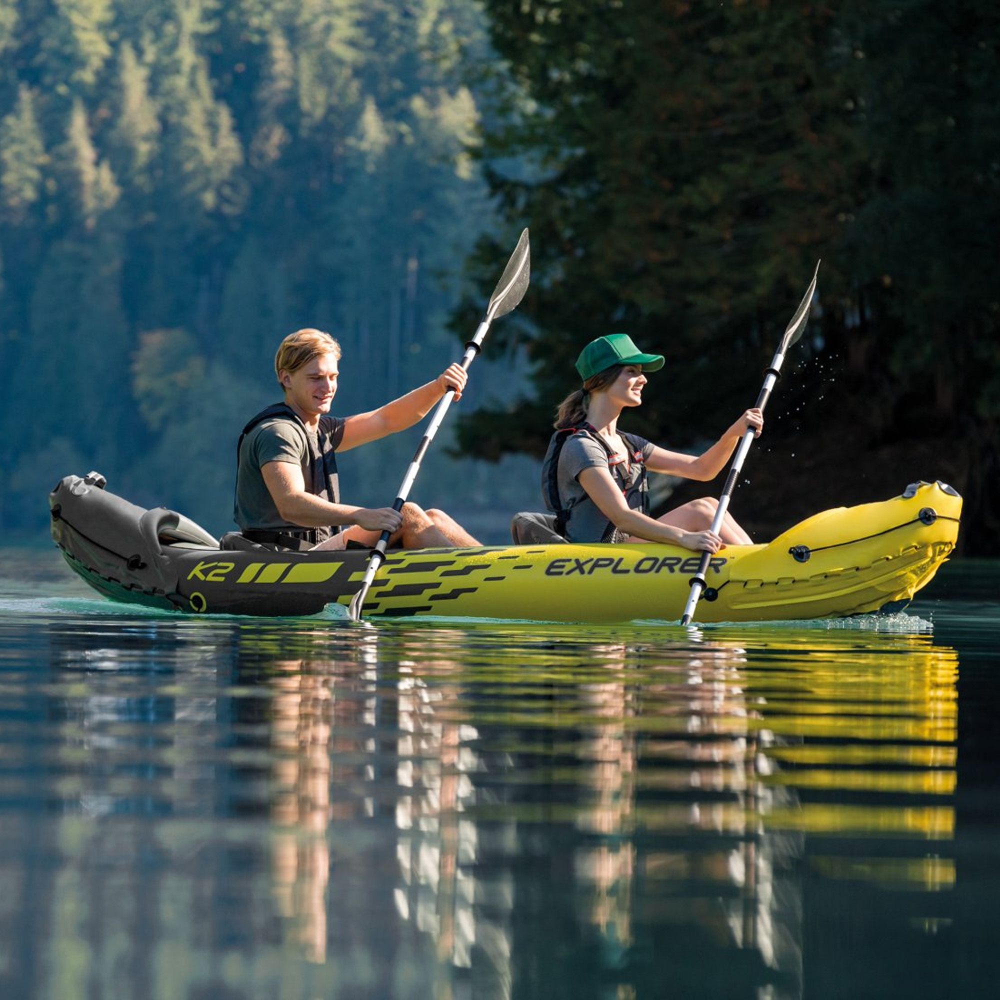 Due persone in kayak in un lago. Il kayak è giallo e nero. Lo sfondo ha alberi e acqua.