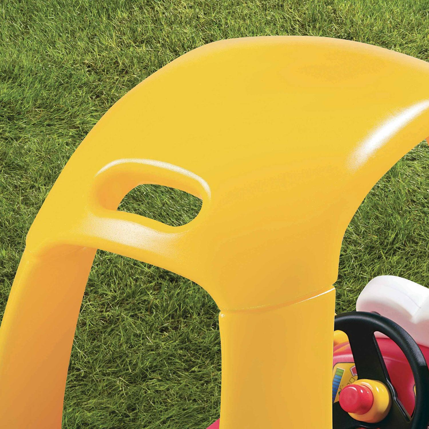 Gelbes Kunststoff-Spielzeugauto-Dach auf grünem Gras, mit einem sichtbaren Lenkrad.