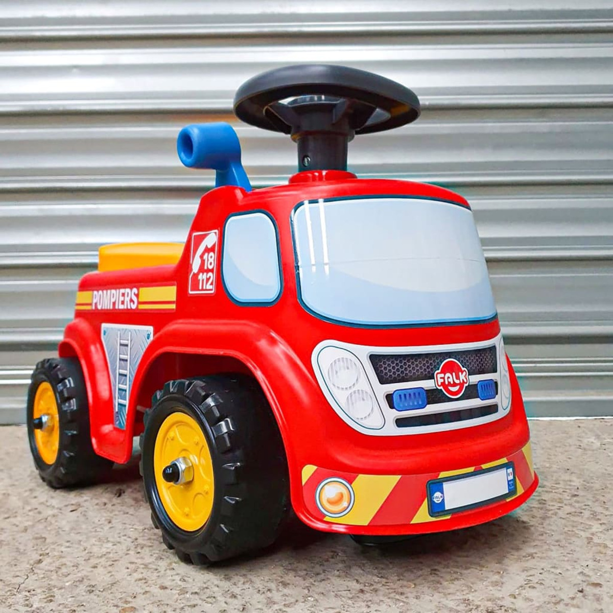 Autobotte giocattolo rossa con dettagli gialli e la scritta 'Pompiers' parcheggiata su una superficie di cemento.
