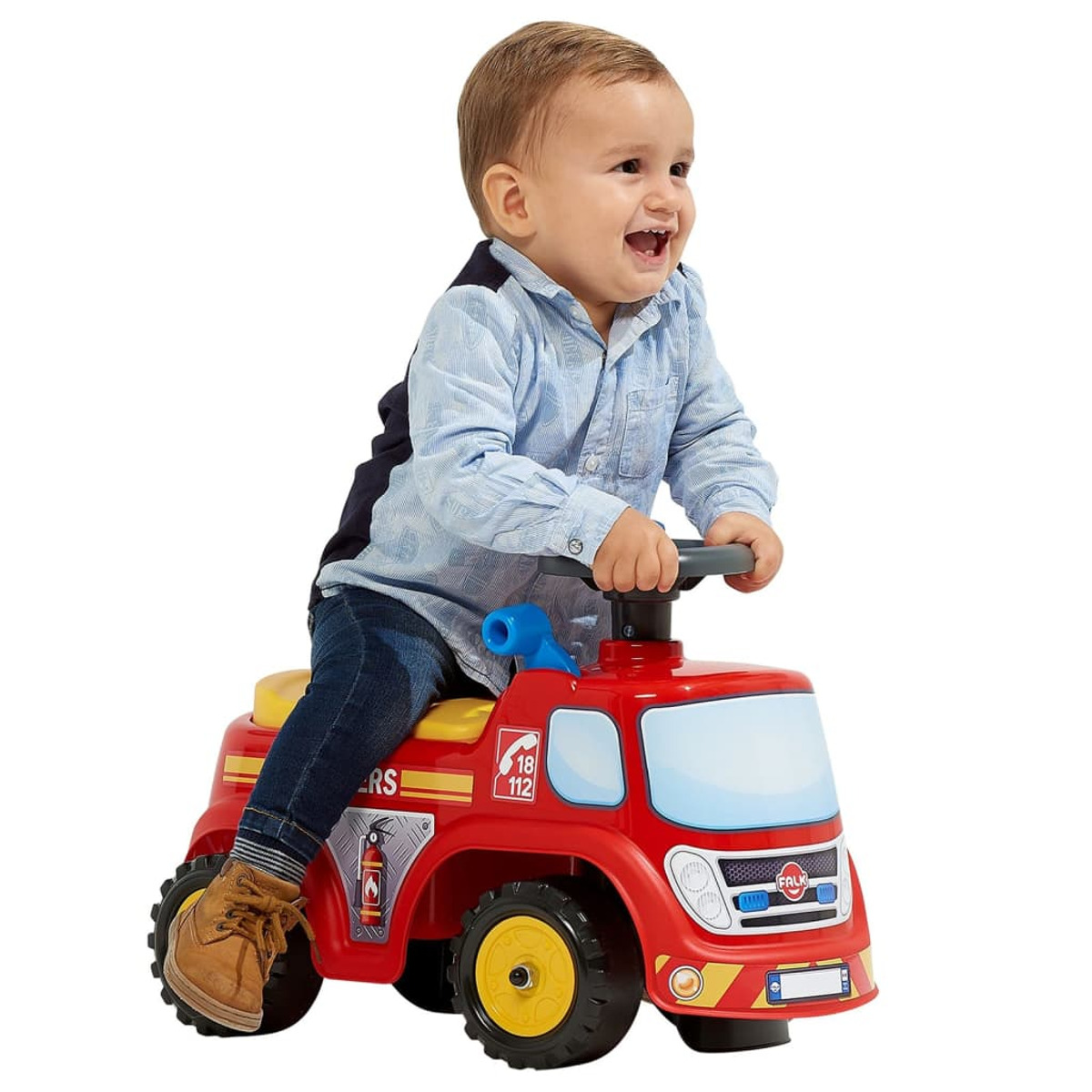 Un bambino seduto su un'autobotte giocattolo rossa, sorridente e con una camicia blu.