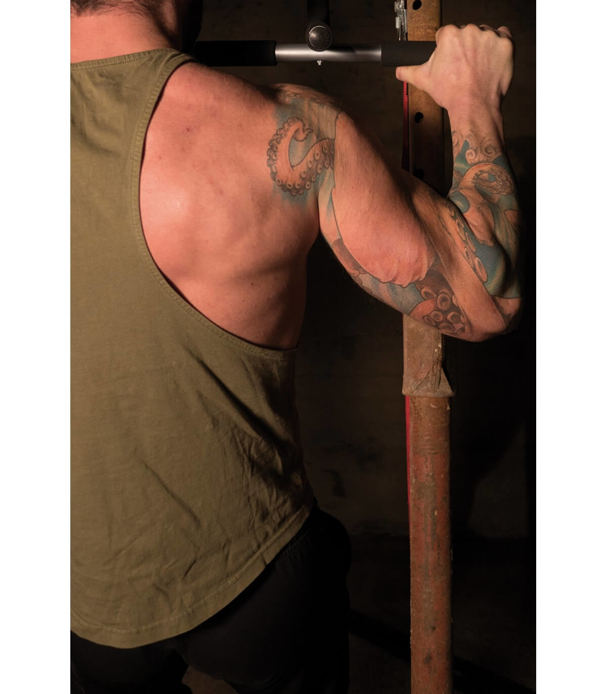 Der Rücken und Arm eines Mannes. Er trägt ein grünes Tanktop und hat ein großes Oktopus-Tattoo auf dem Arm.
