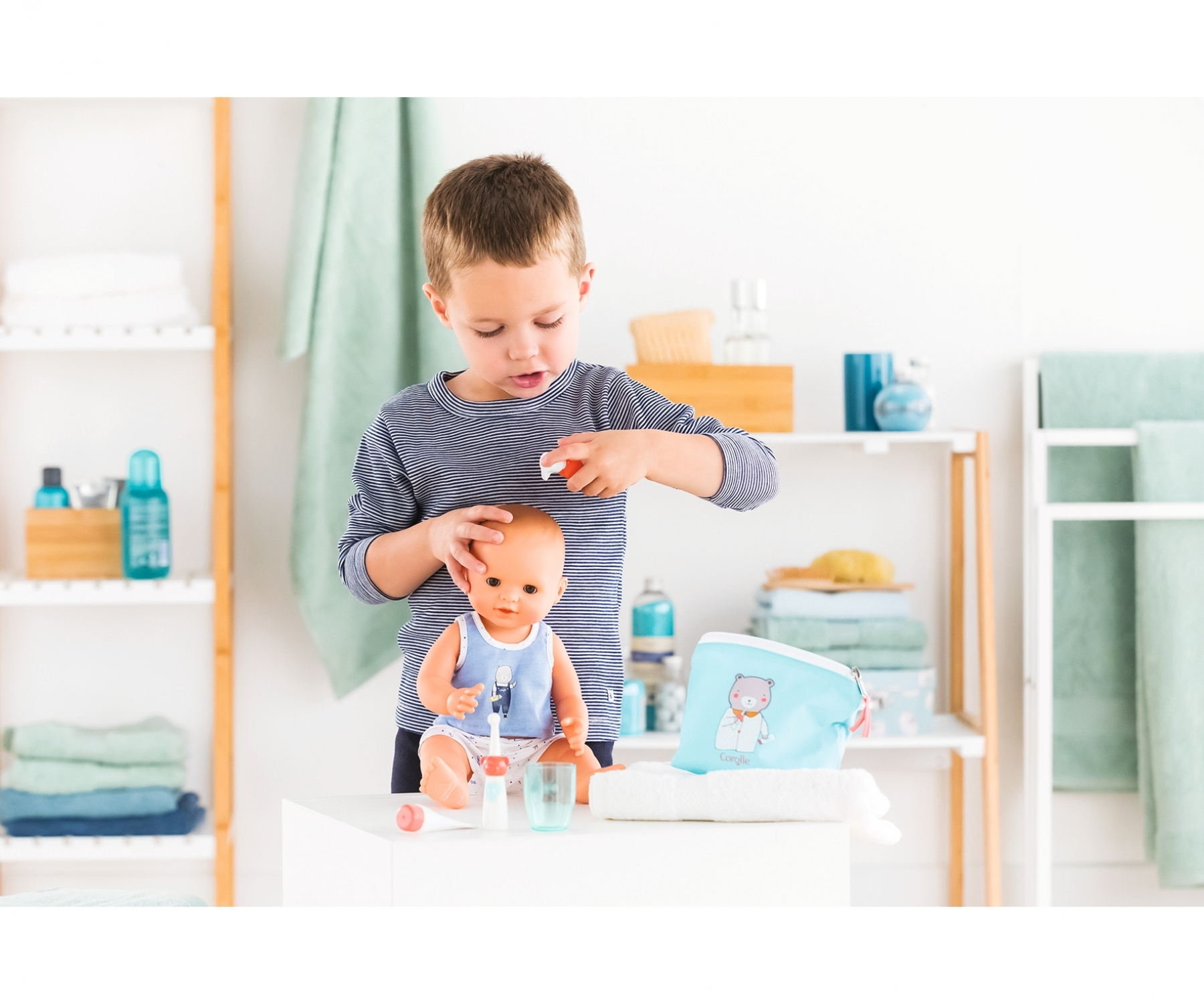 Dziecko bawi się lalką i akcesoriami w łazience. Obecna jest niebieska torba.