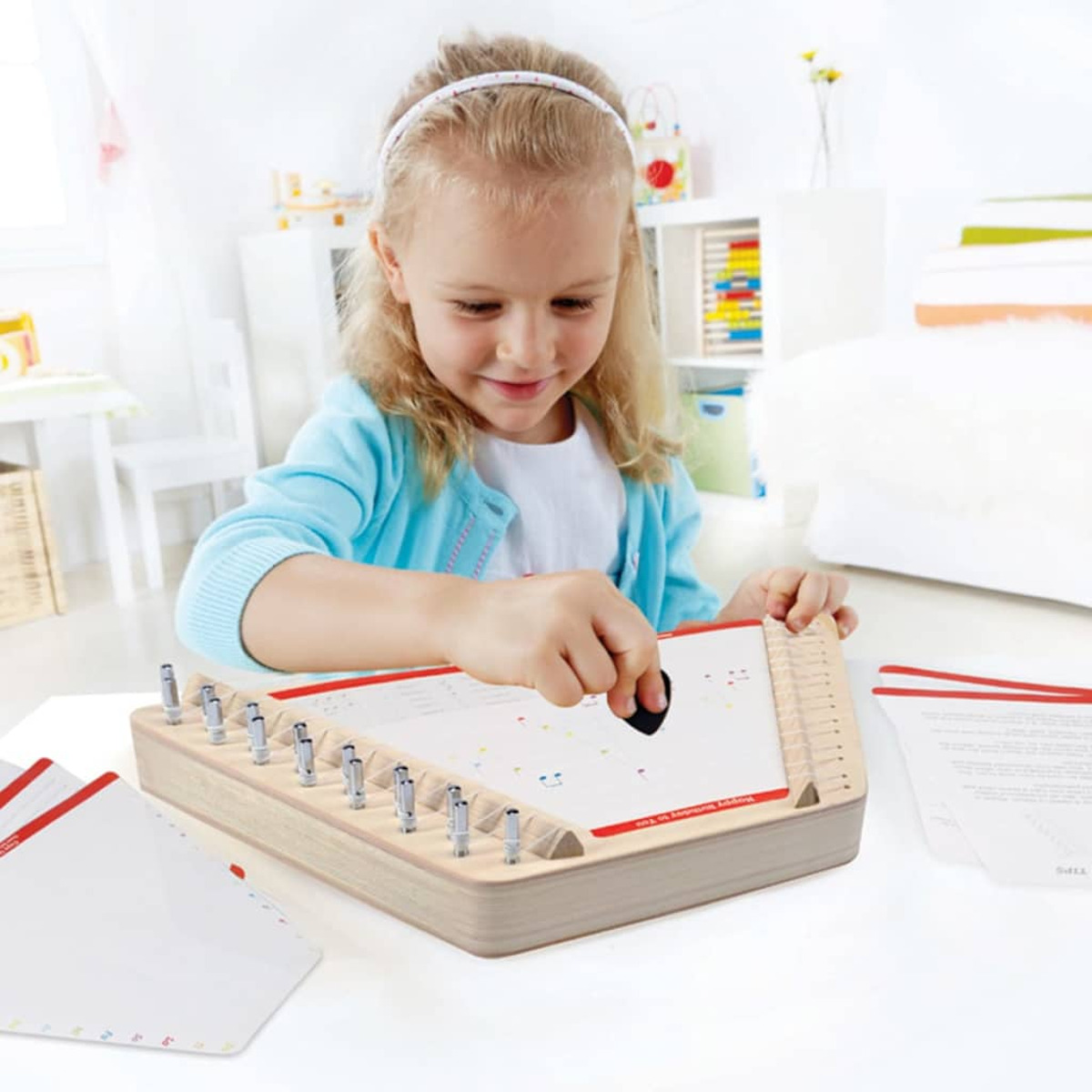 Una niña toca un instrumento musical. Usa una herramienta negra. El instrumento está en una mesa blanca.