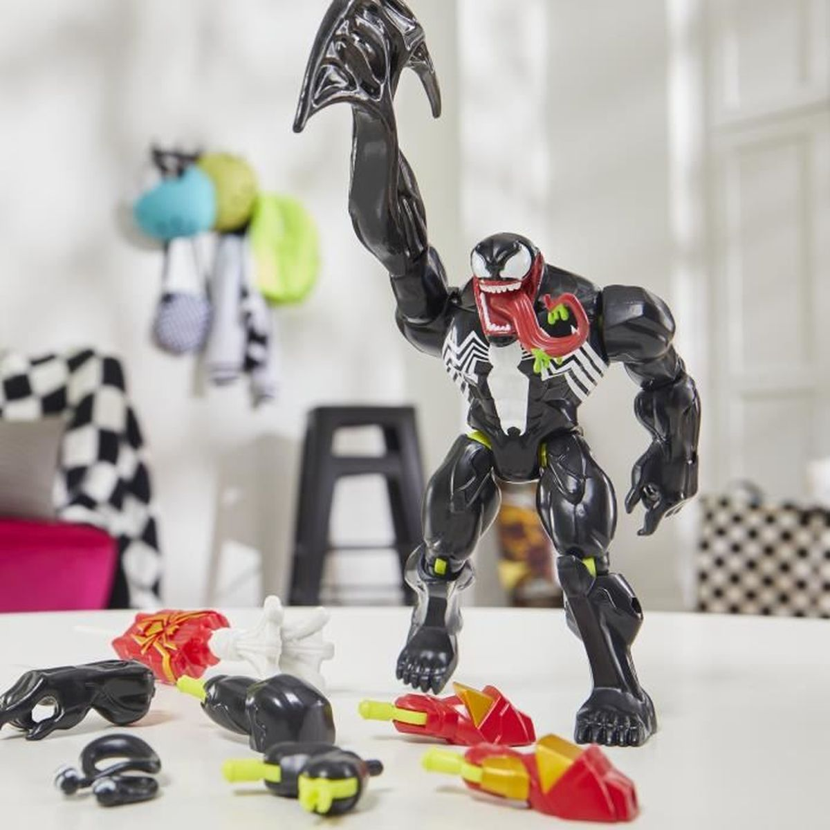 Una figura de acción de Venom negra con múltiples accesorios, de pie sobre una mesa. Tiene un pecho blanco y una lengua roja.