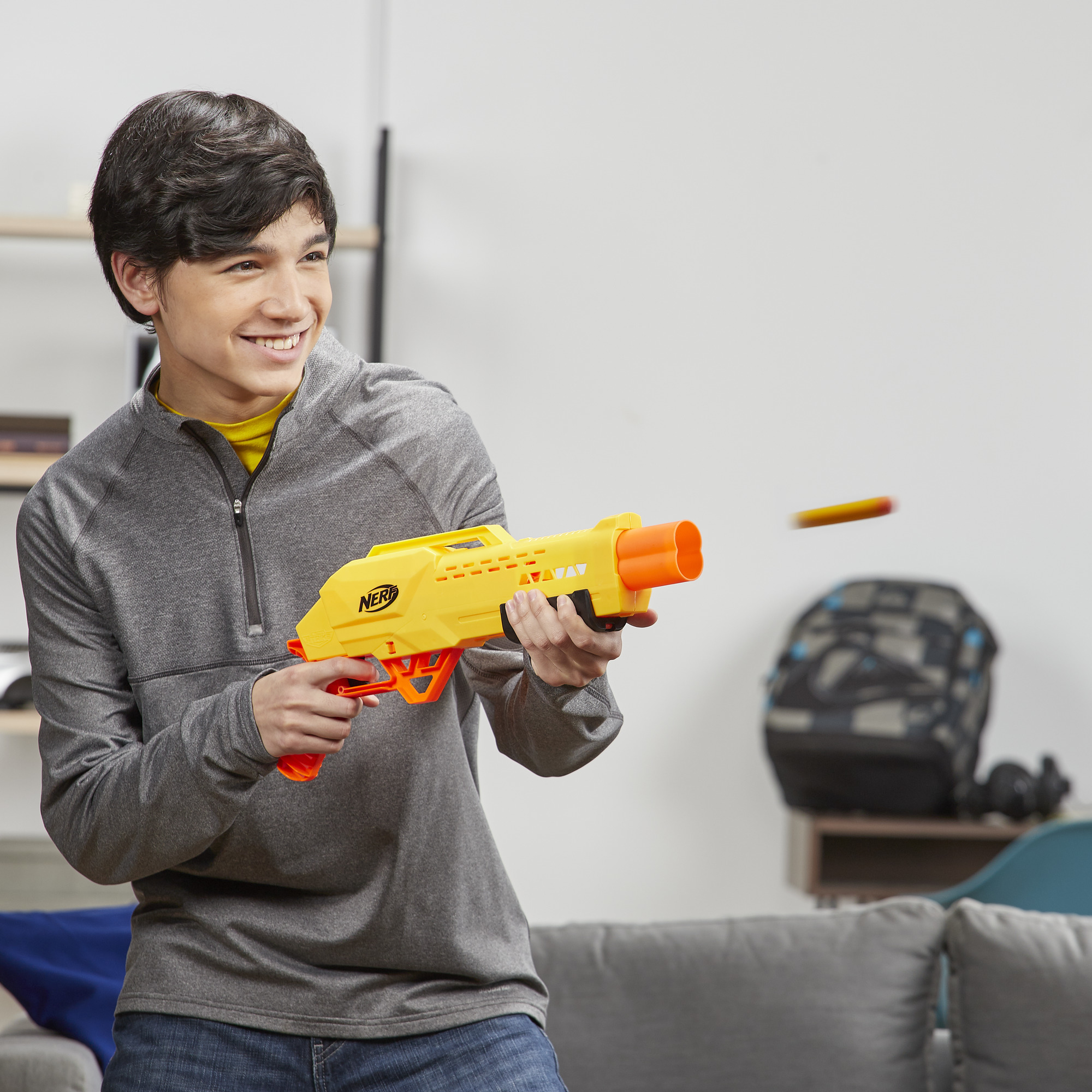 Un niño apuntando con una pistola Nerf amarilla con detalles naranjas.