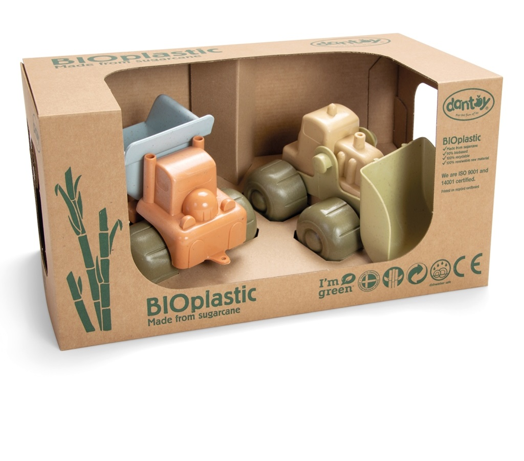 Dwie zabawki ciężarówki budowlane w kartonowym pudełku. Pomarańczowa wywrotka, beżowa ładowarka czołowa, zielone pudełko.