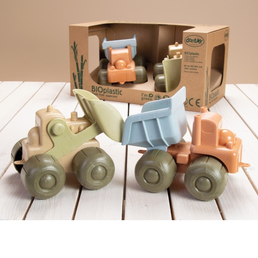 Zabawkowe ciężarówki w pudełku. Jedna ma łopatę, druga wywrotkę. Jasnobrązowy i niebieski.