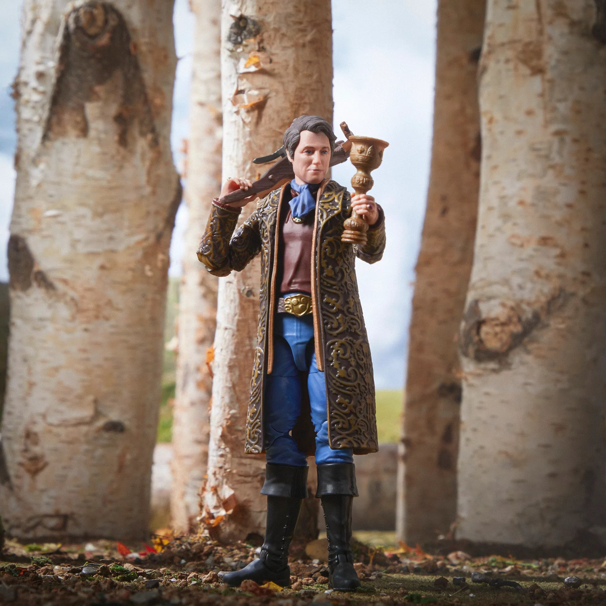 Action figure di un uomo con un calice, in piedi tra betulle.