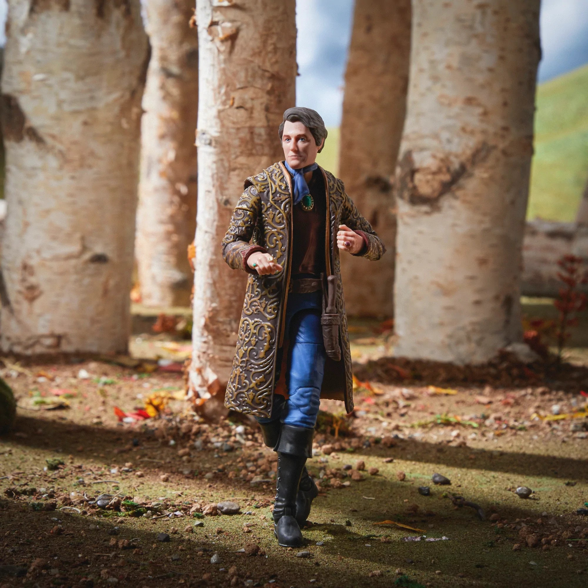 Una statuetta di un uomo con un cappotto fantasia cammina in un bosco di betulle.