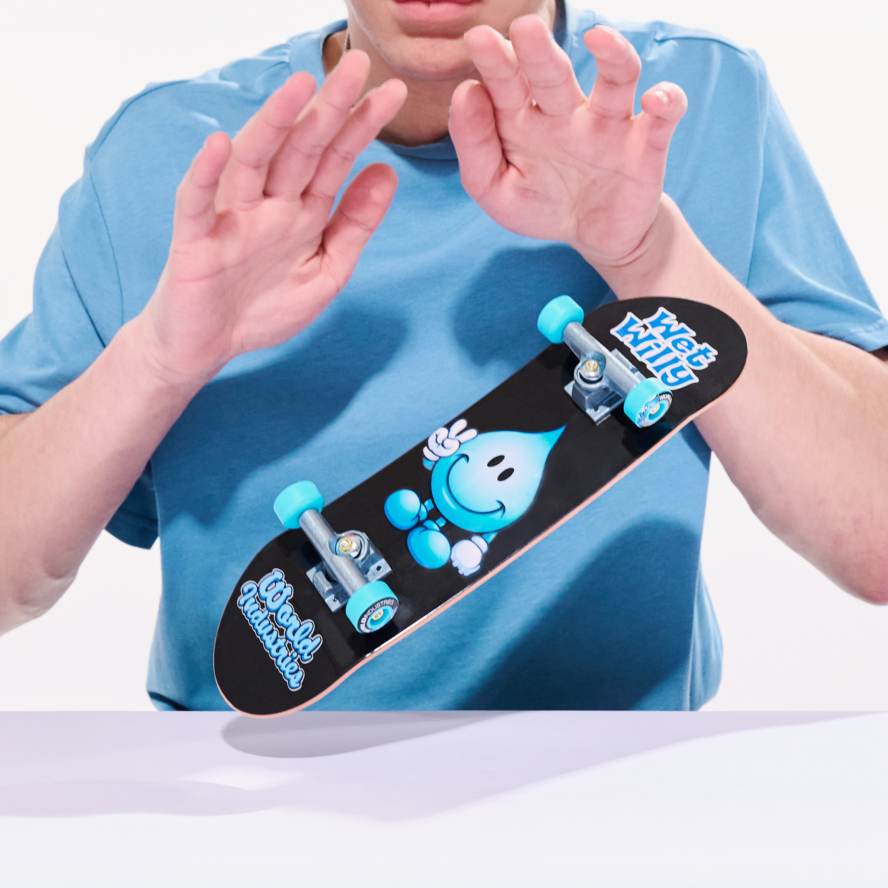 Osoba trzymająca czarną deskorolkę z niebiesko-białym wzorem.