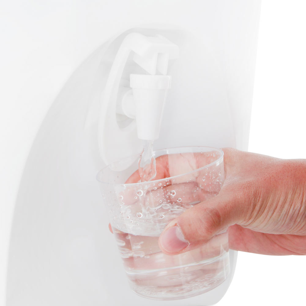 Dłoń napełniająca szklankę wodą z białego dystrybutora wody. Przezroczysta szklanka.