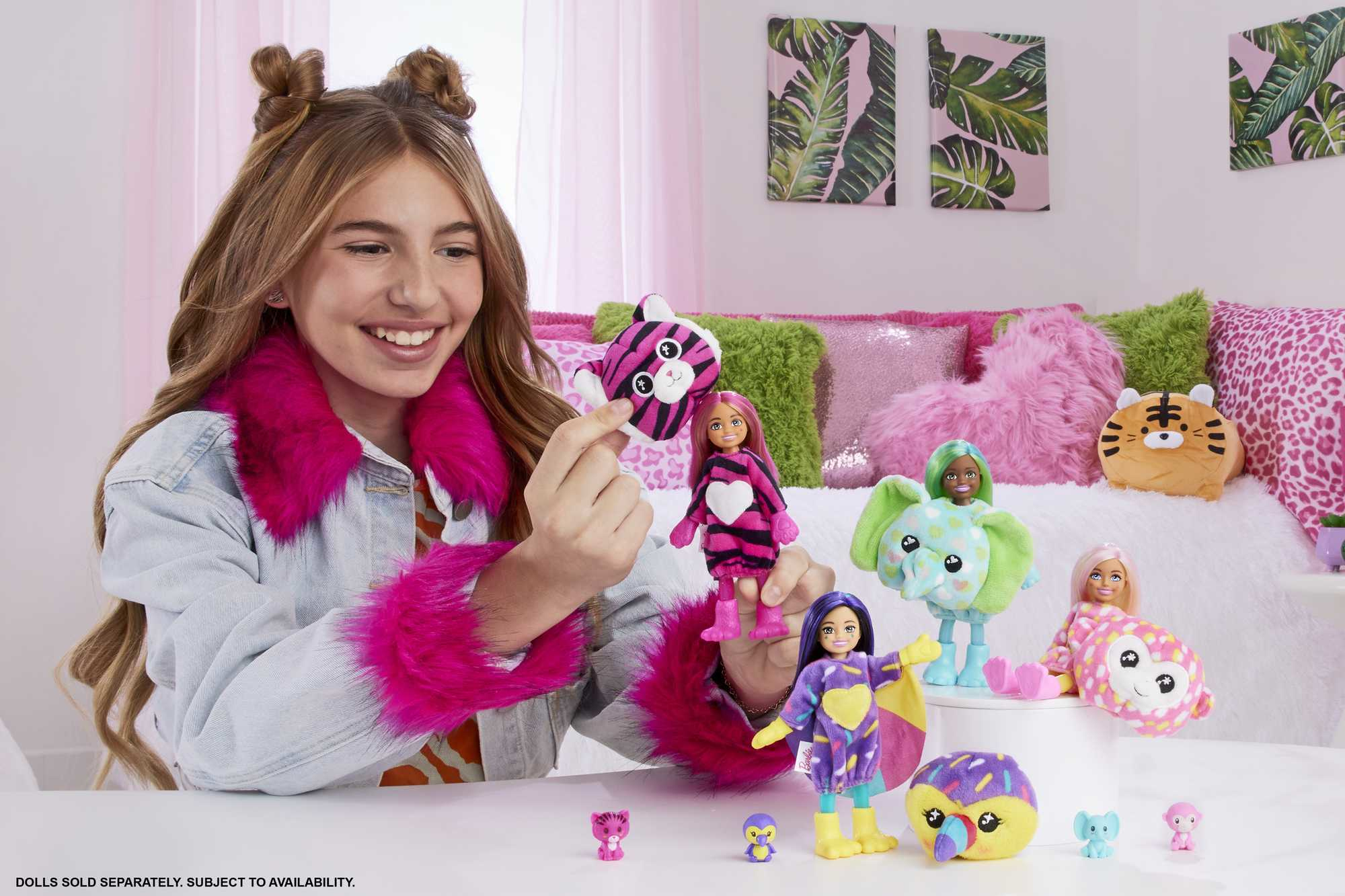 Mädchen mit Puppen. Puppen sind in verschiedenen Kostümen. Hintergrund ist ein Bett mit rosa und grünen Kissen.