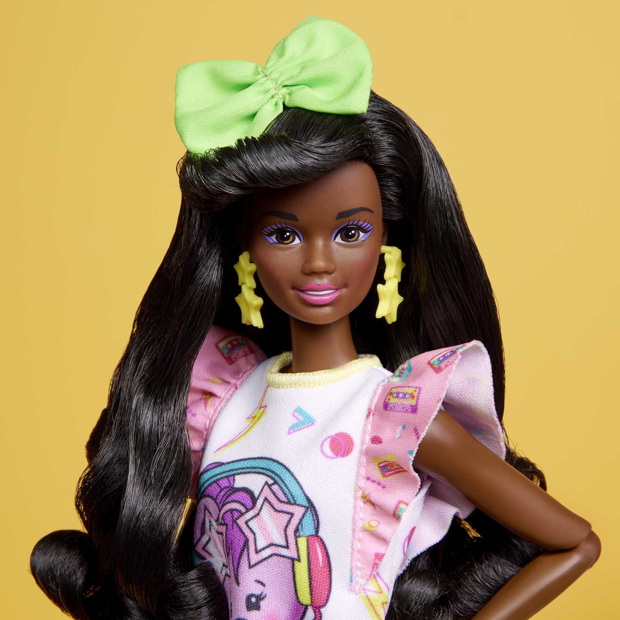 Schwarze Barbie-Puppe mit langen Haaren und neon-grüner Schleife. Gelber Hintergrund.