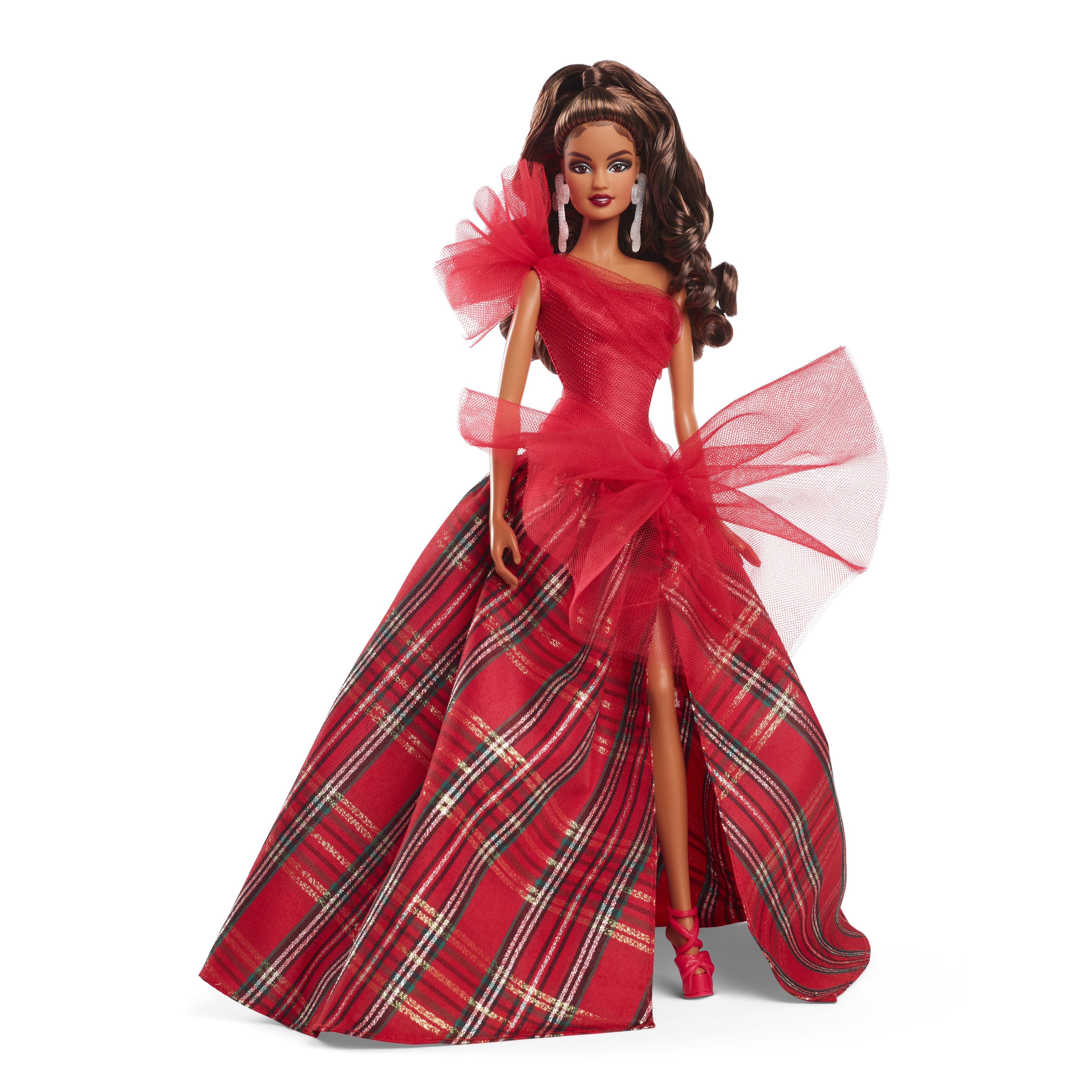 Eine Barbie-Puppe in einem roten Schottenkleid mit hohem Schlitz. Sie hat lange braune Haare und steht vor weißem Hintergrund.