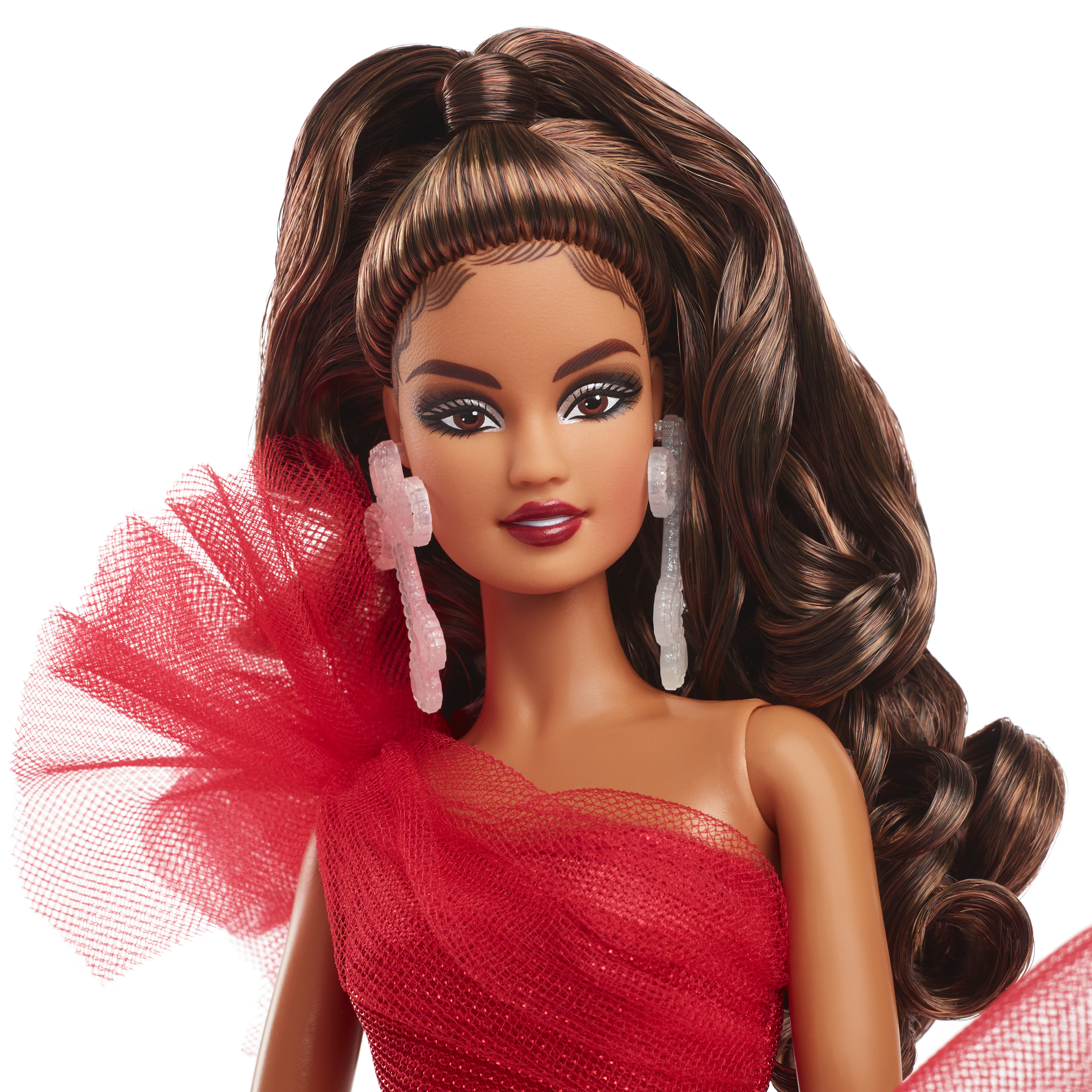 Nahaufnahme des Gesichts einer Puppe. Die Puppe hat braune Haare, ein rotes Kleid und Ohrringe. Weißer Hintergrund.