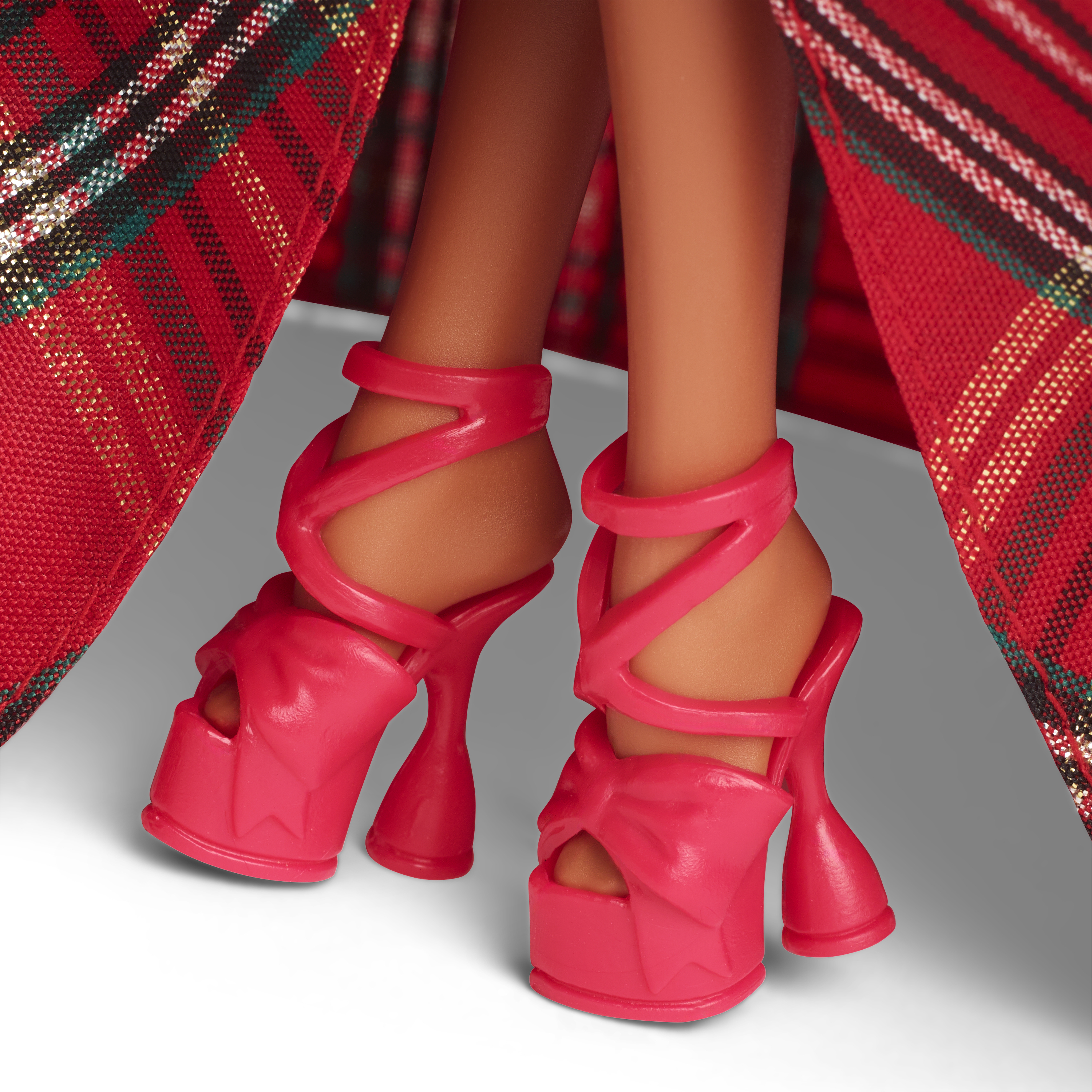 Nahaufnahme von pinkfarbenen Plateau-Absätzen an einer Barbie-Puppe, vor einem rot-goldenen Karokleid.
