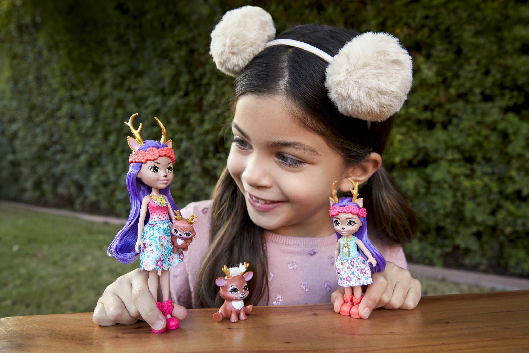 Mädchen mit Puppen. Puppen tragen Hirschgeweihe und Blumenkleider.