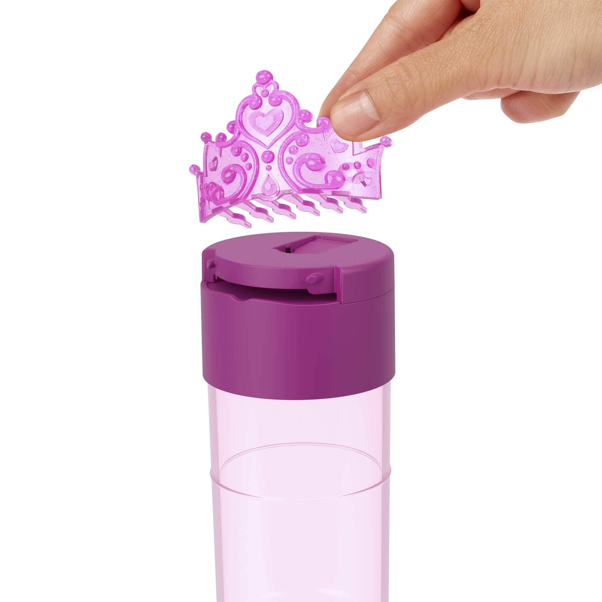Ręka umieszczająca fioletową tiarę na fioletowym pojemniku z pokrywką, prawdopodobnie pojemniku na zabawki.