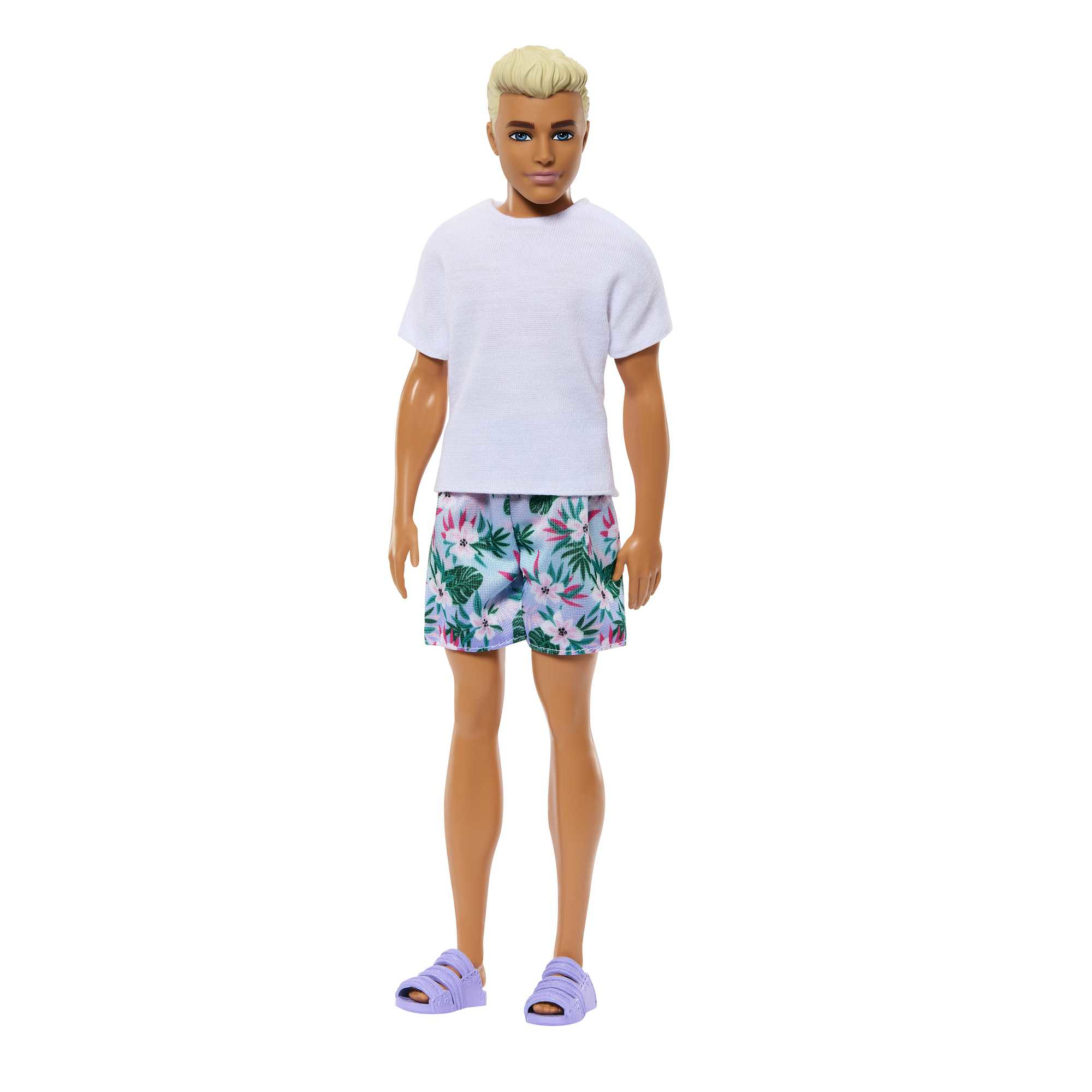 Eine Ken-Puppe steht mit weißem T-Shirt, Blumenshorts und lila Sandalen.